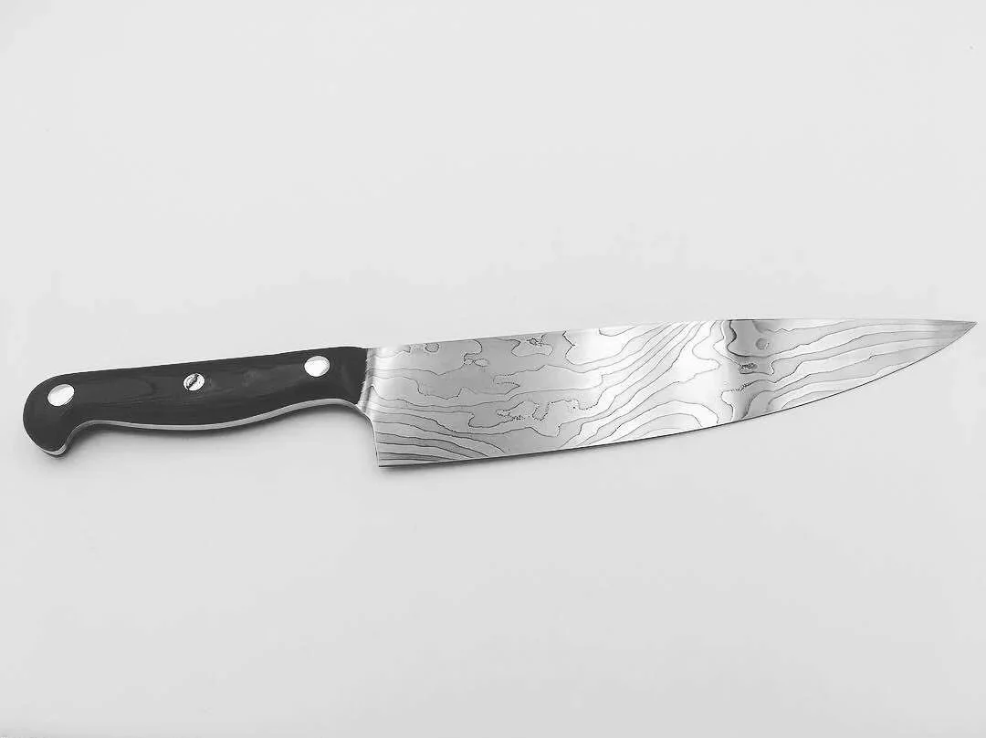 Chef's knife, the first I ever made, and one I still own because of it. It has some issues, but I use it nearly every day. (2019)
Blade: Laminated 1095 and 15N20, with pure nickel sheet for contrast.
Handle: Black canvas micarta.