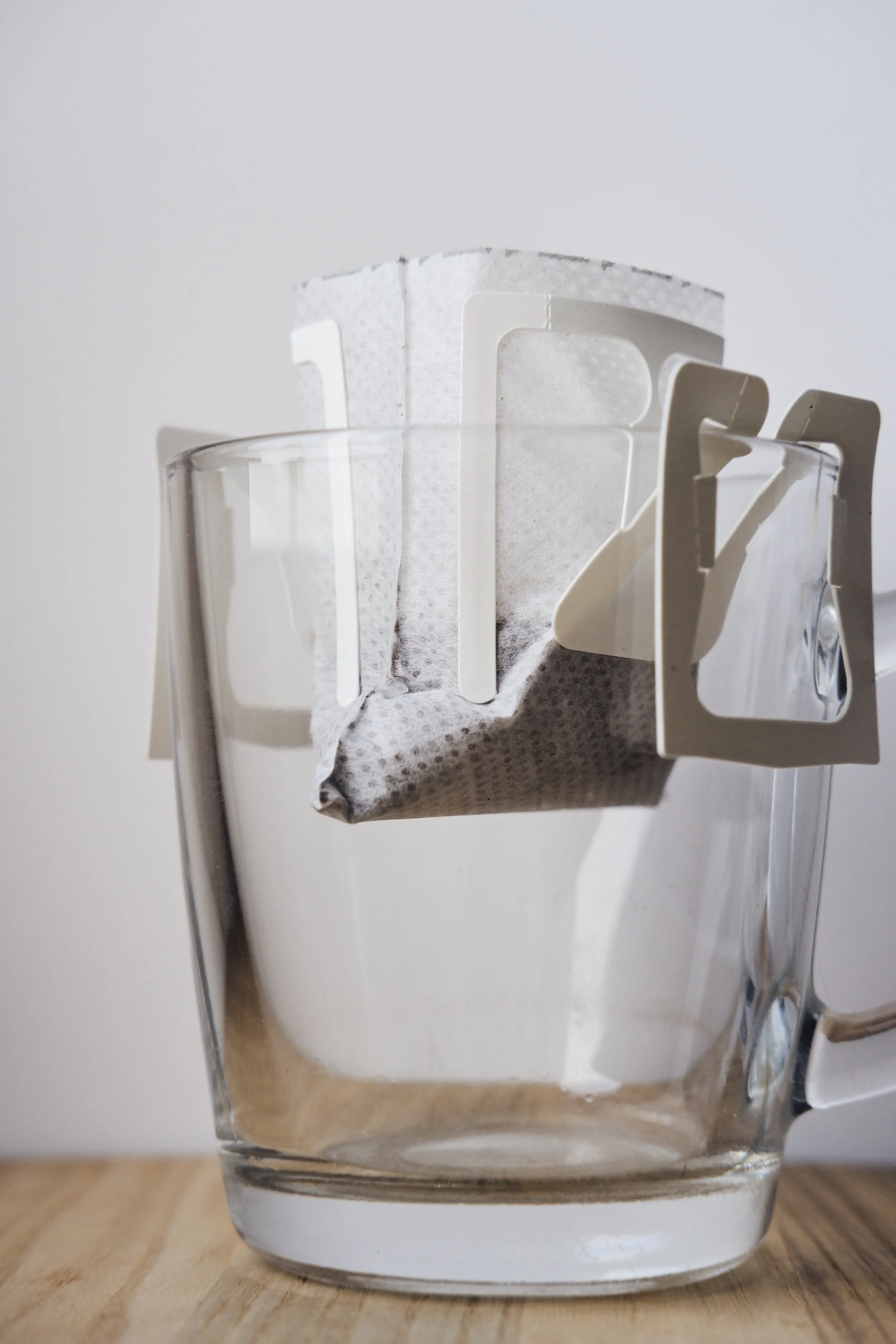 drip-coffee-with-ground-black-arabica-coffee-large-glass-cup-closeup-portion-drip-coffee-per-cup-cup-with-paper-drip-coffee-stands-wooden-board-white-background-closeup.jpg