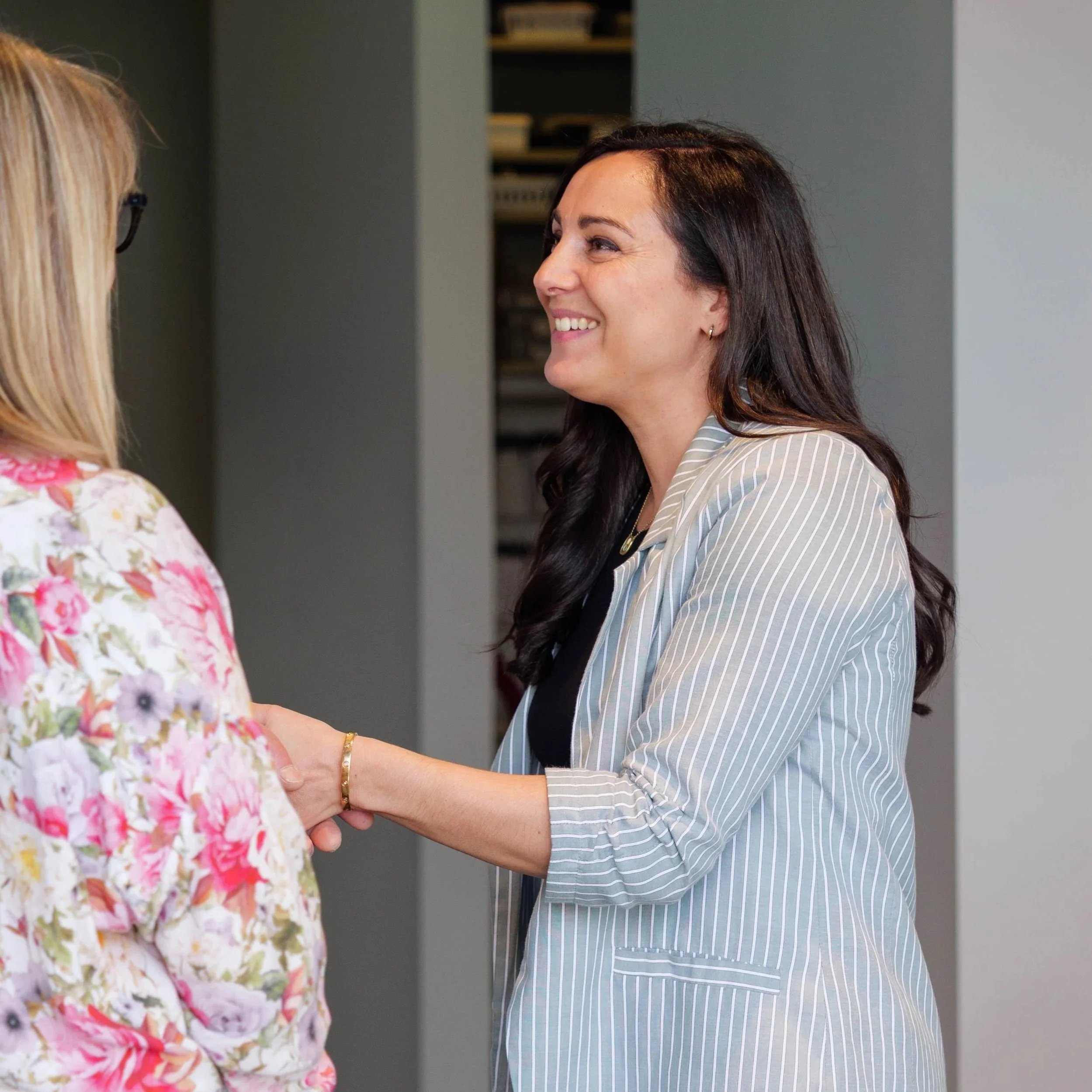 Katrin Hobson, engaged in a friendly conversation indoors, at an audiology clinic