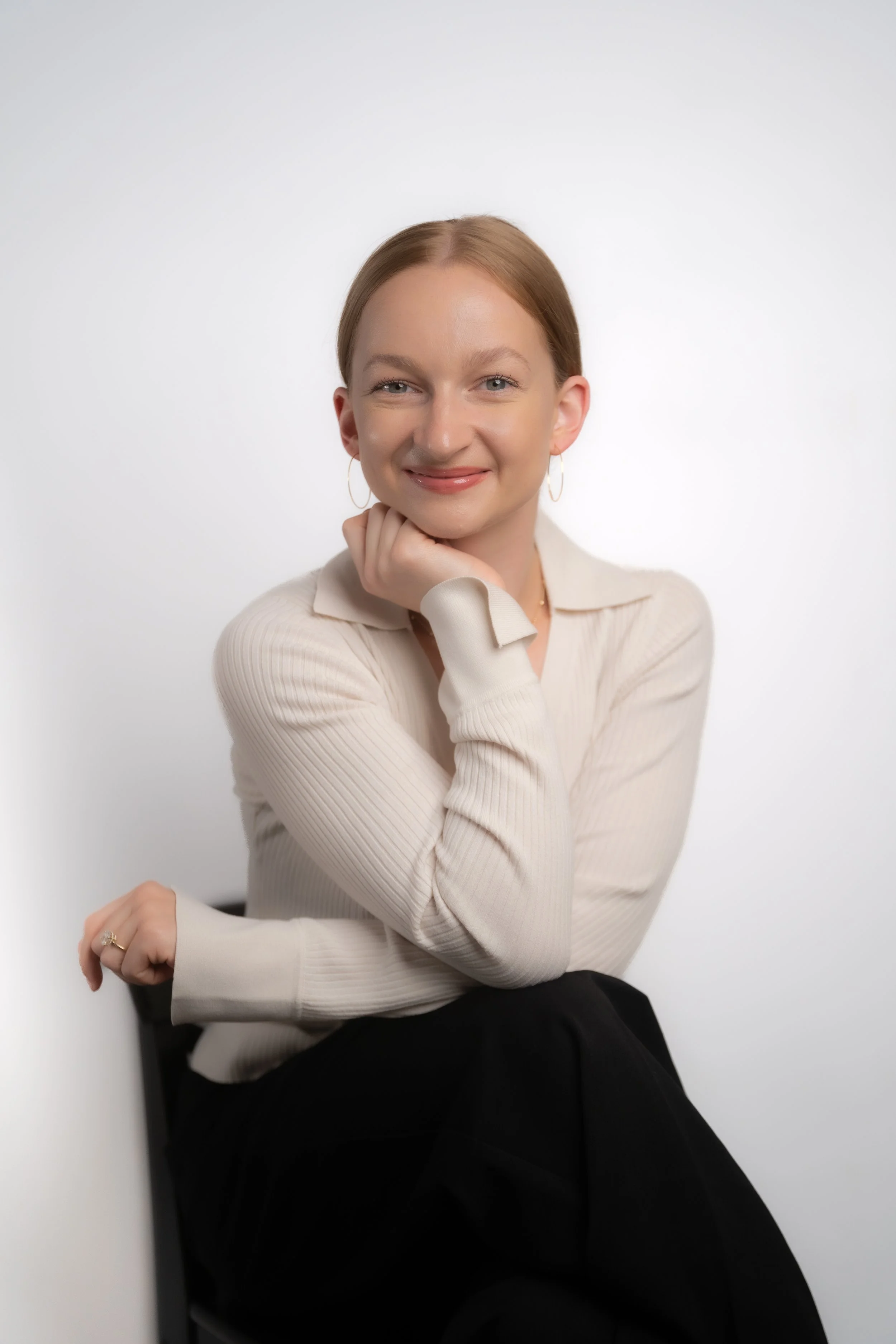 Maggie Armstrong sitting on a chair with red hair posing for a headshot.