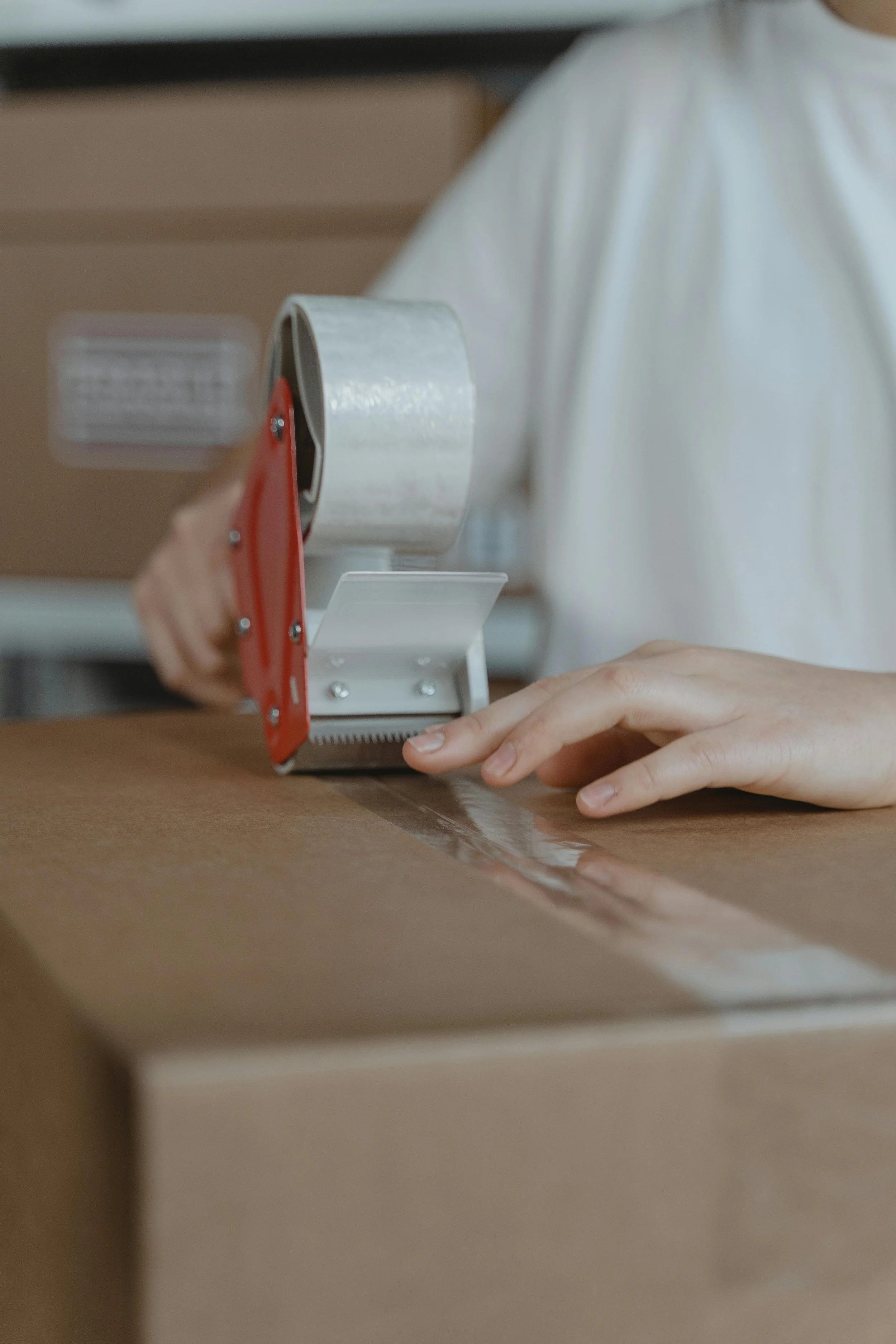 Hands taping a cardboard box during a move, symbolizing life changes connected to grief and transitions.