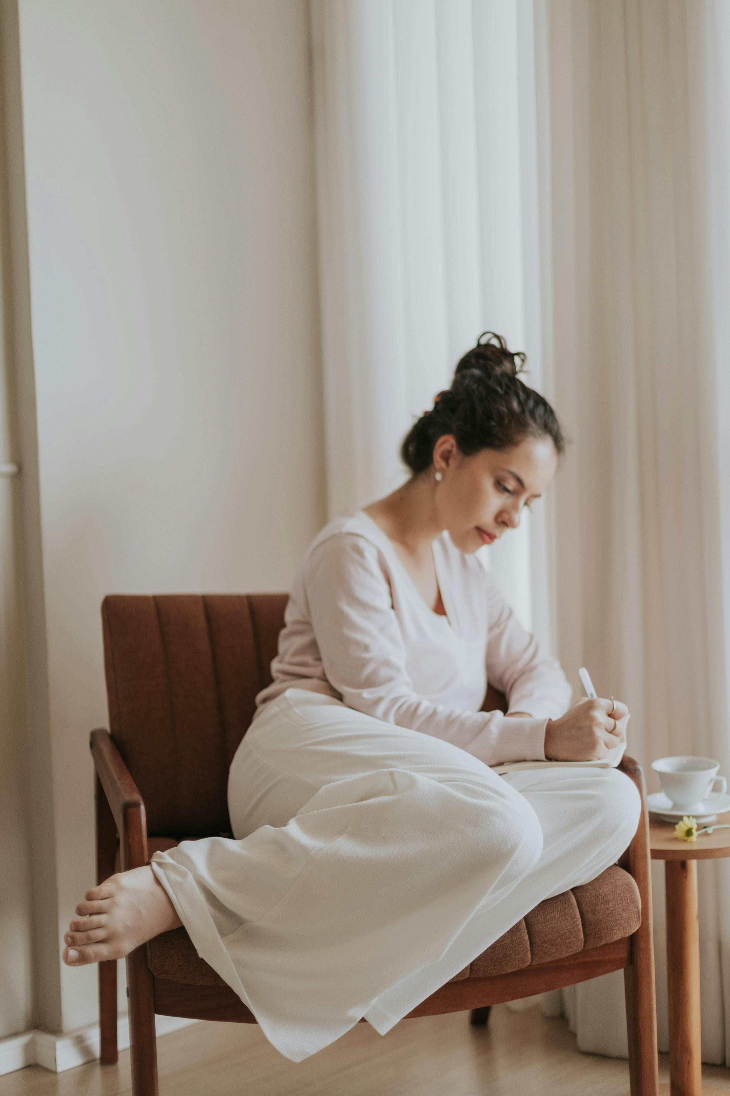 Woman sitting in a chair writing in a notebook — processing trauma and grief through therapy with Dr. Sarah Williams