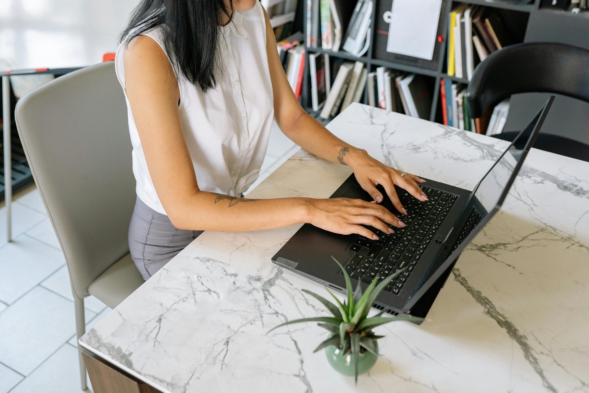 Professional woman working at her desk, showing signs of mental fatigue and burnout while typing on her laptop.