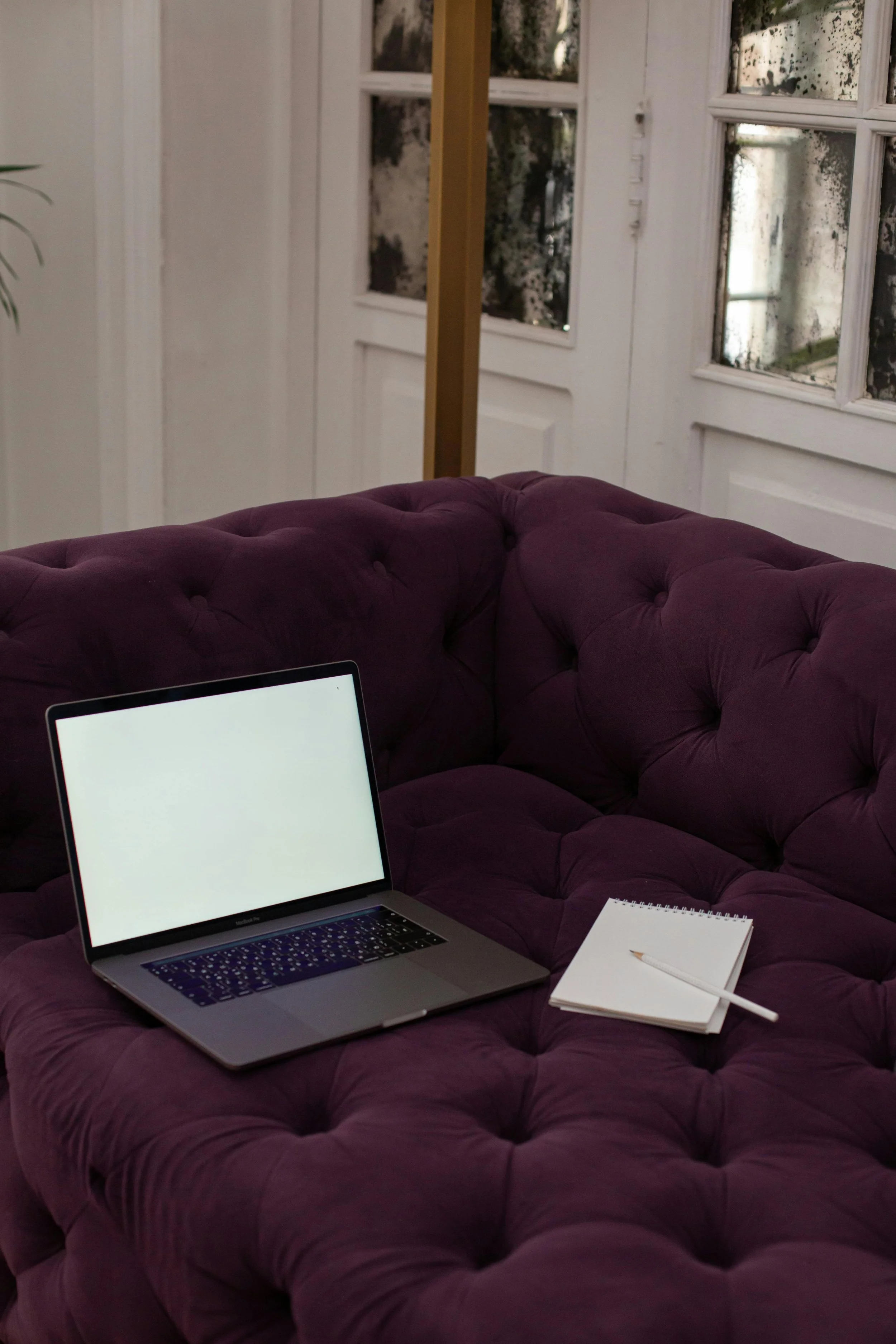 Laptop, notepad, and pen arranged on a couch, representing a comfortable online therapy setting.