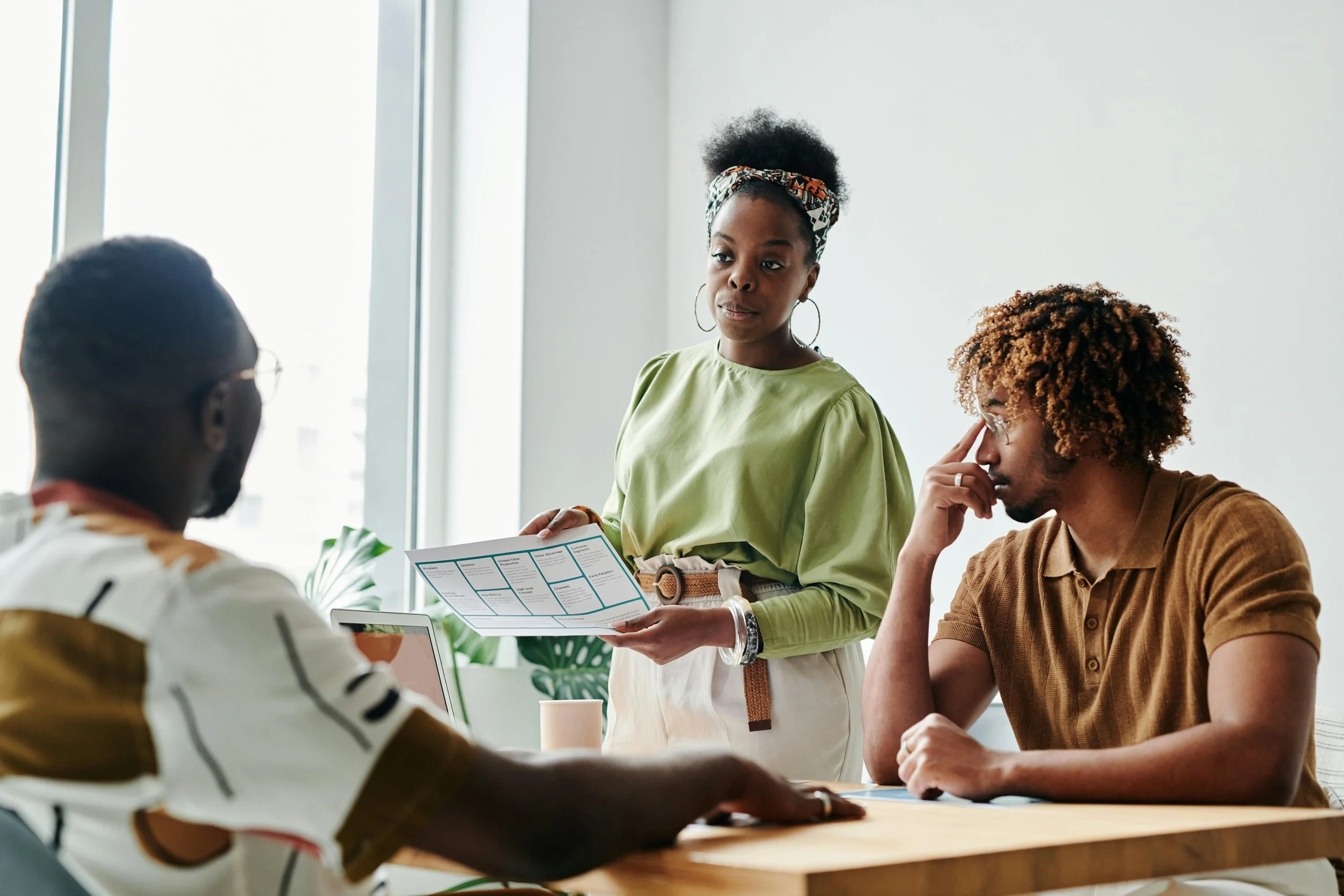 Black woman with colleagues in a professional workplace setting — navigating job loss and identity with Dr. Sarah Williams