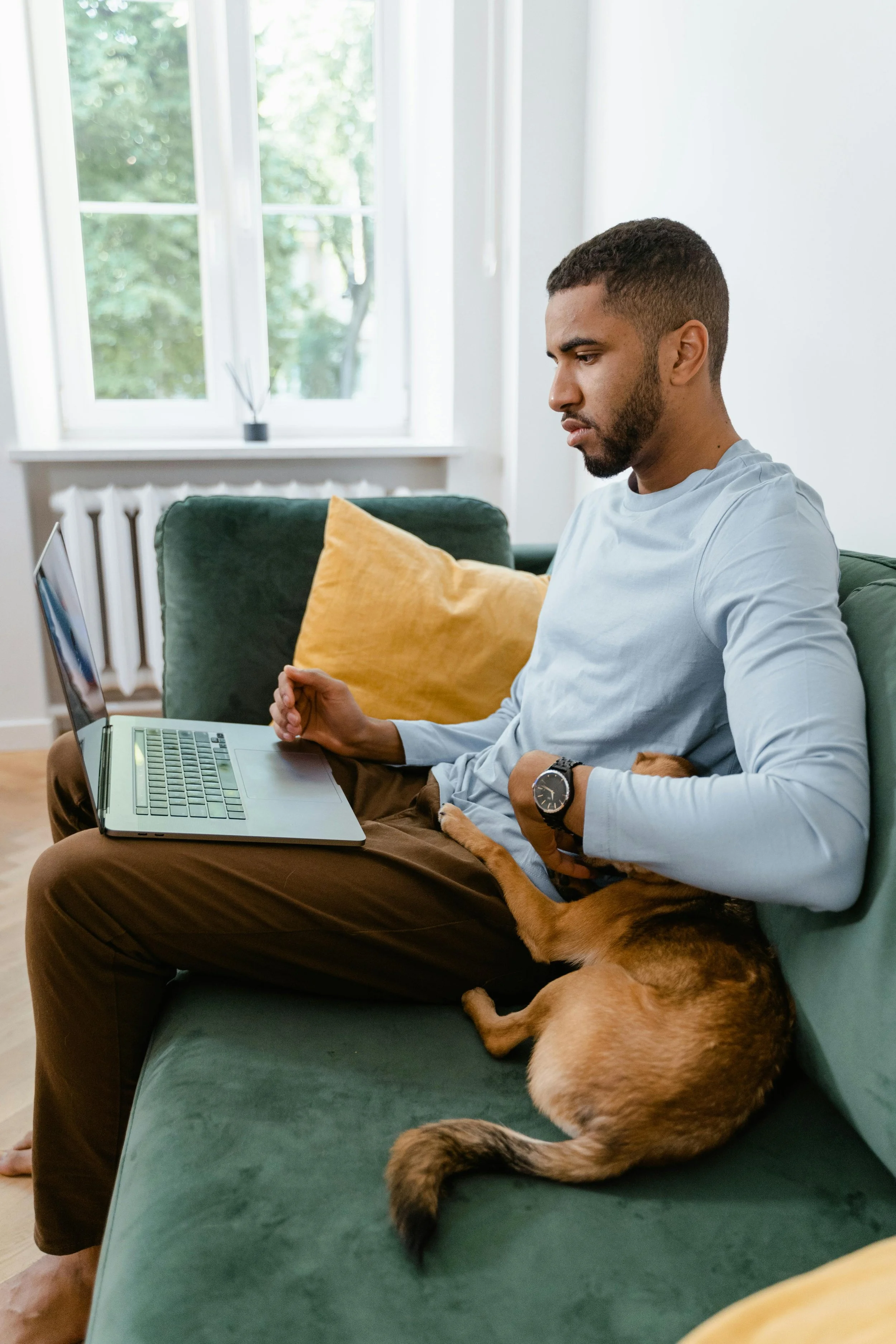 Professional man working on a laptop at home with his dog, illustrating common trauma patterns in high-functioning leaders
