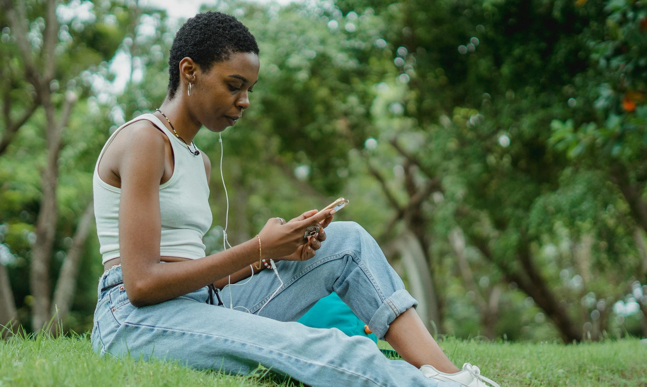 Black woman sitting outside looking at her phone — navigating relational trauma and intimate partner violence with Dr. Sarah Williams