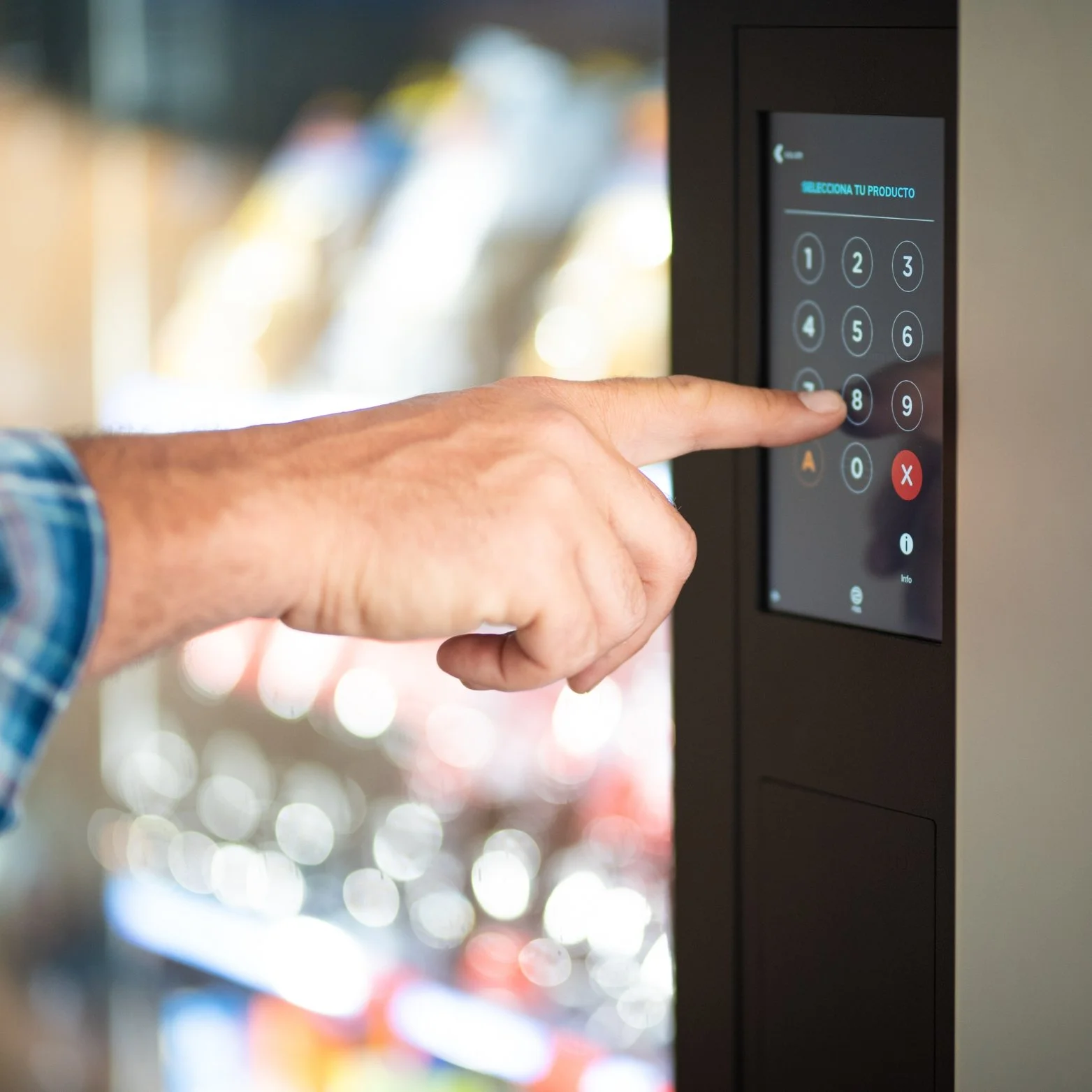 A person's hand pressing the number 8 on a touchscreen vending machine.