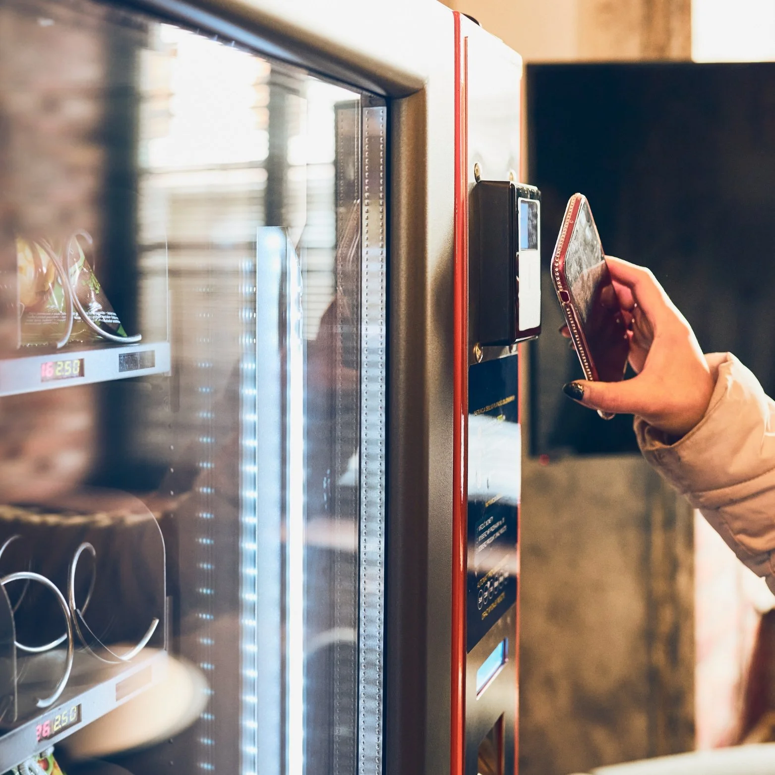 A person using a smartphone near a vending machine.