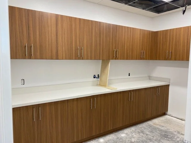 Empty kitchen with wooden upper and lower cabinets, a white countertop, and an open space where a section of the countertop is missing, possibly for a sink or appliance installation.