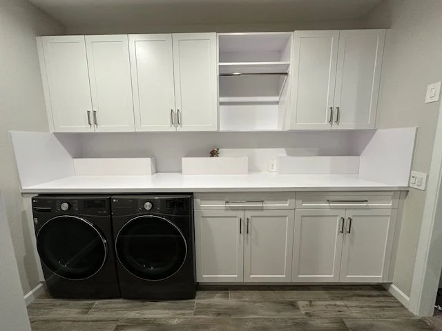 Laundry room with white cabinets, countertop, and a black washer and dryer.