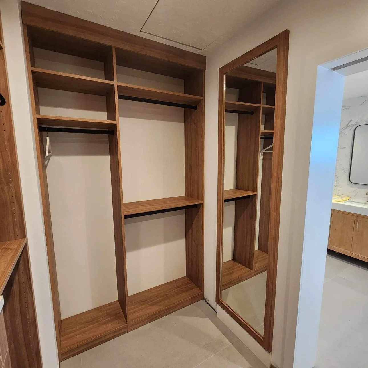 Empty wooden closet with a built-in mirror in a modern room.