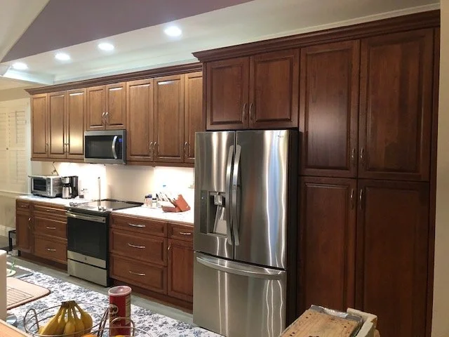 Kitchen with wooden cabinets, stainless steel refrigerator, microwave, oven, and small appliances on the countertop.