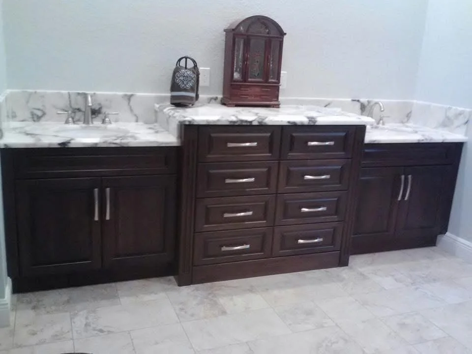 Bathroom vanity with dark wood cabinets, a marble countertop, and a double sink, with decorative items on top.