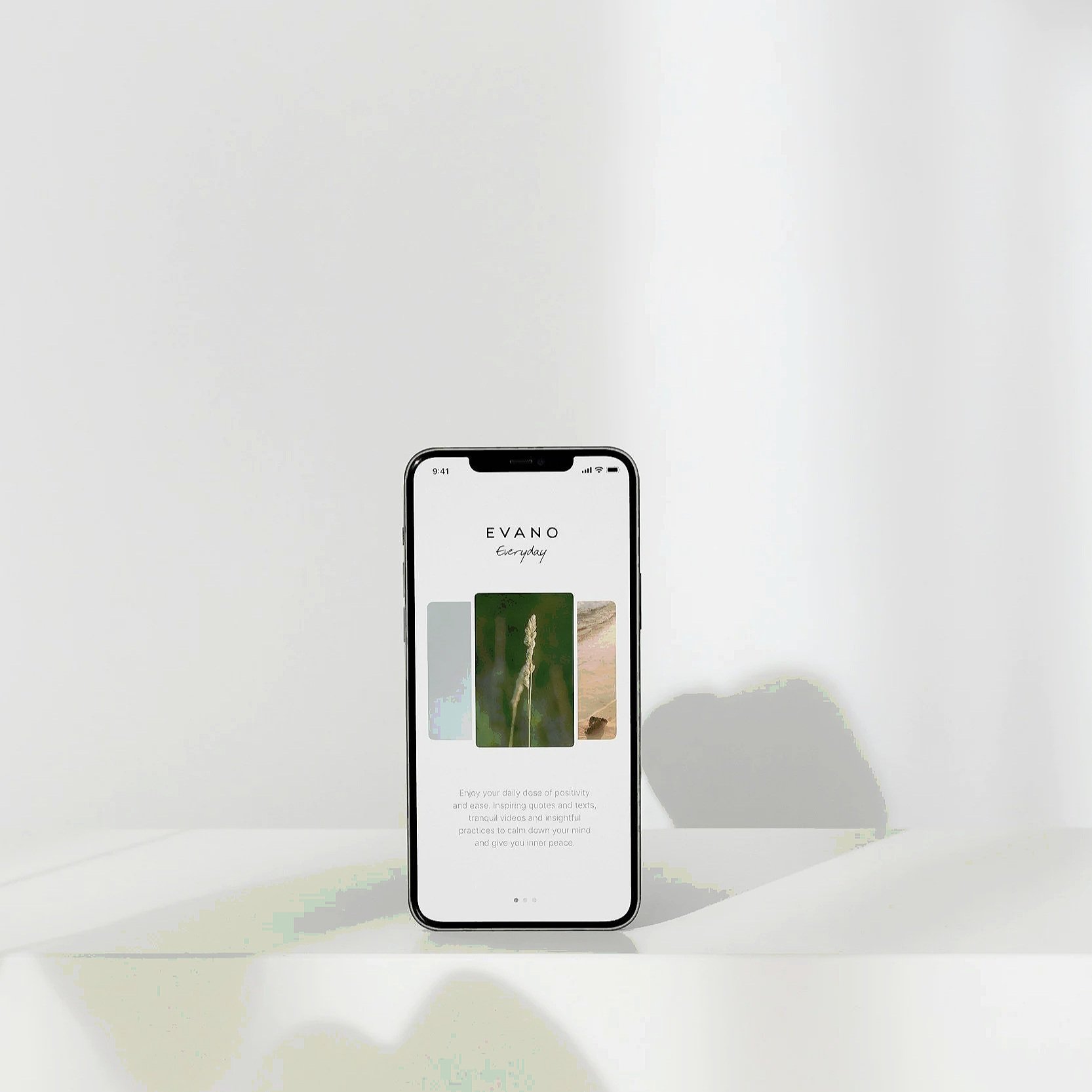 A smartphone displaying the EVANO app, standing on a white surface with its shadow cast on the background wall.