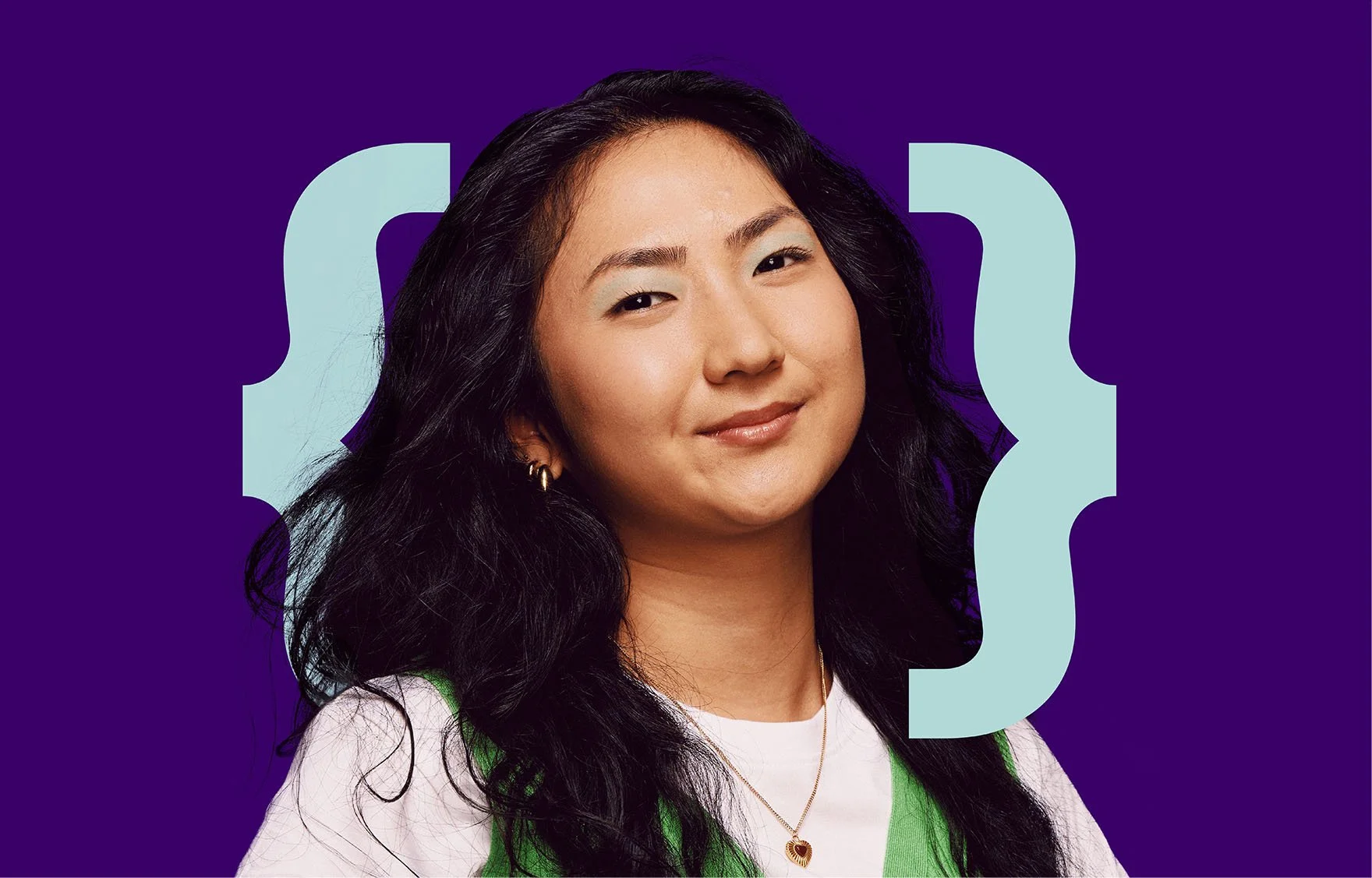 A young woman with long dark curly hair, wearing a white shirt with green accents, gold hoop earrings, and a gold necklace with a red heart pendant, smiling at the camera against a purple background with light blue curly brackets.