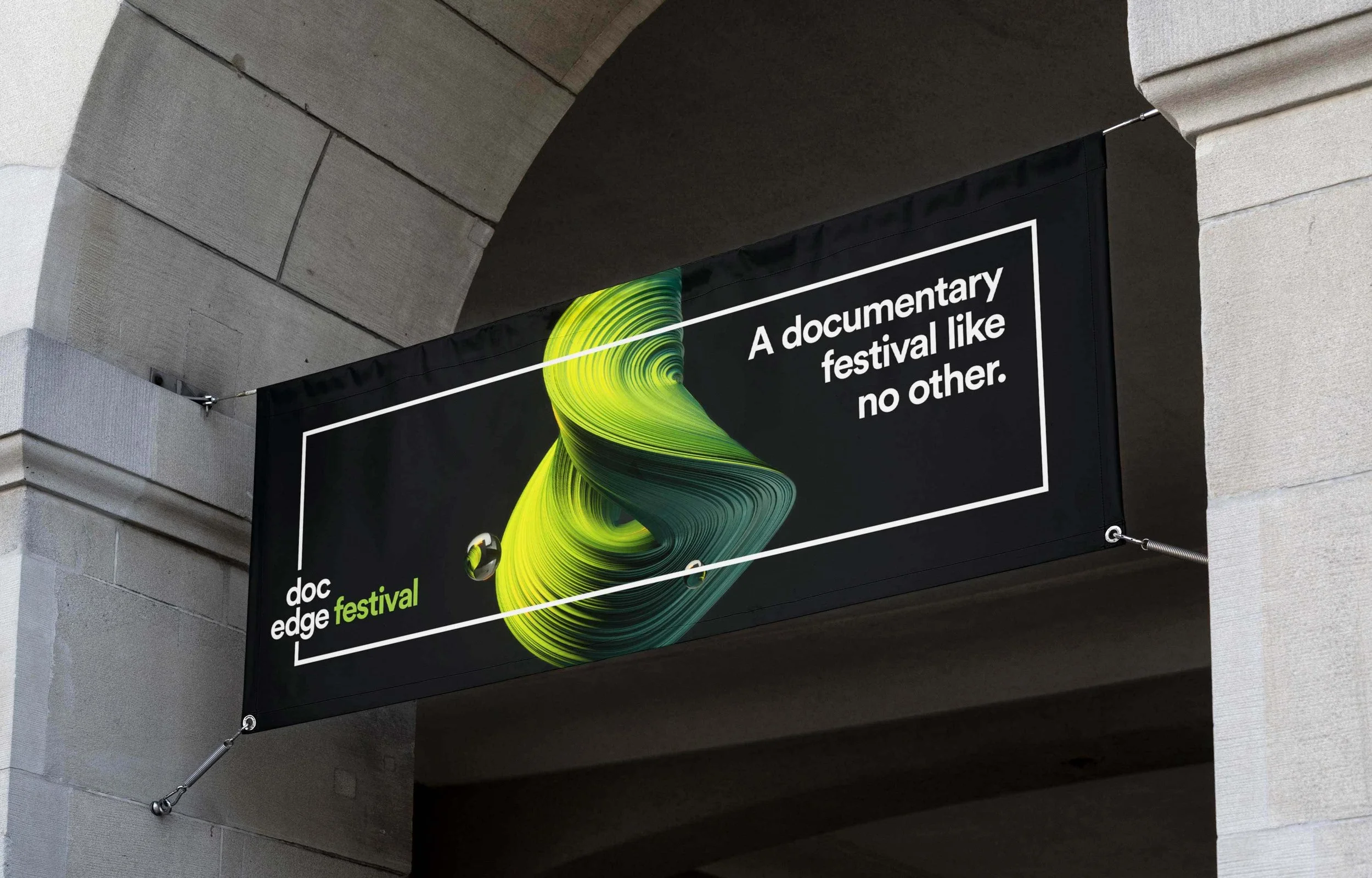 Banner for the doc edge festival with a black background, a vibrant green and yellow abstract swirl in the center, and white text that reads 'A documentary festival like no other.' Additional text in the lower left corner says 'doc edge festival' in white and green.