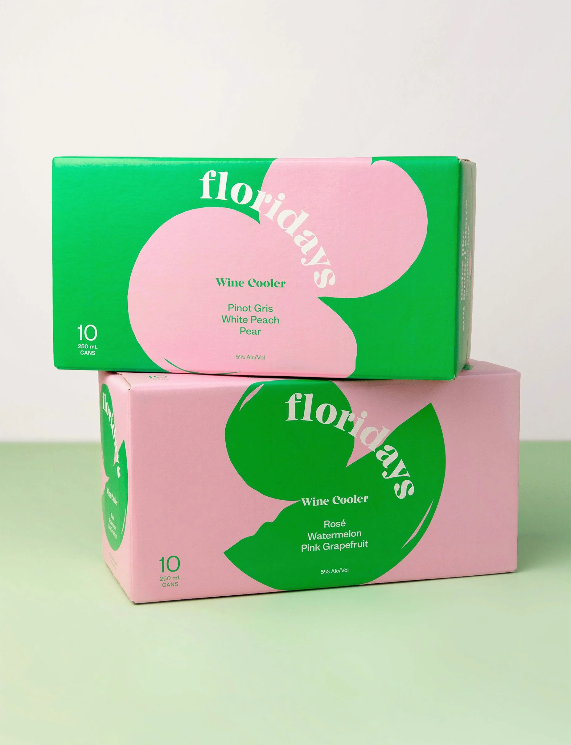 Two boxes of Florida's Wine Coolers, one with a pink and green design featuring flavors like Pinot Gris, White Peach, and Pear, and the other with pink and green design featuring flavors like Rosé, Watermelon, and Pink Grapefruit, placed on a pastel green surface against a plain white background.