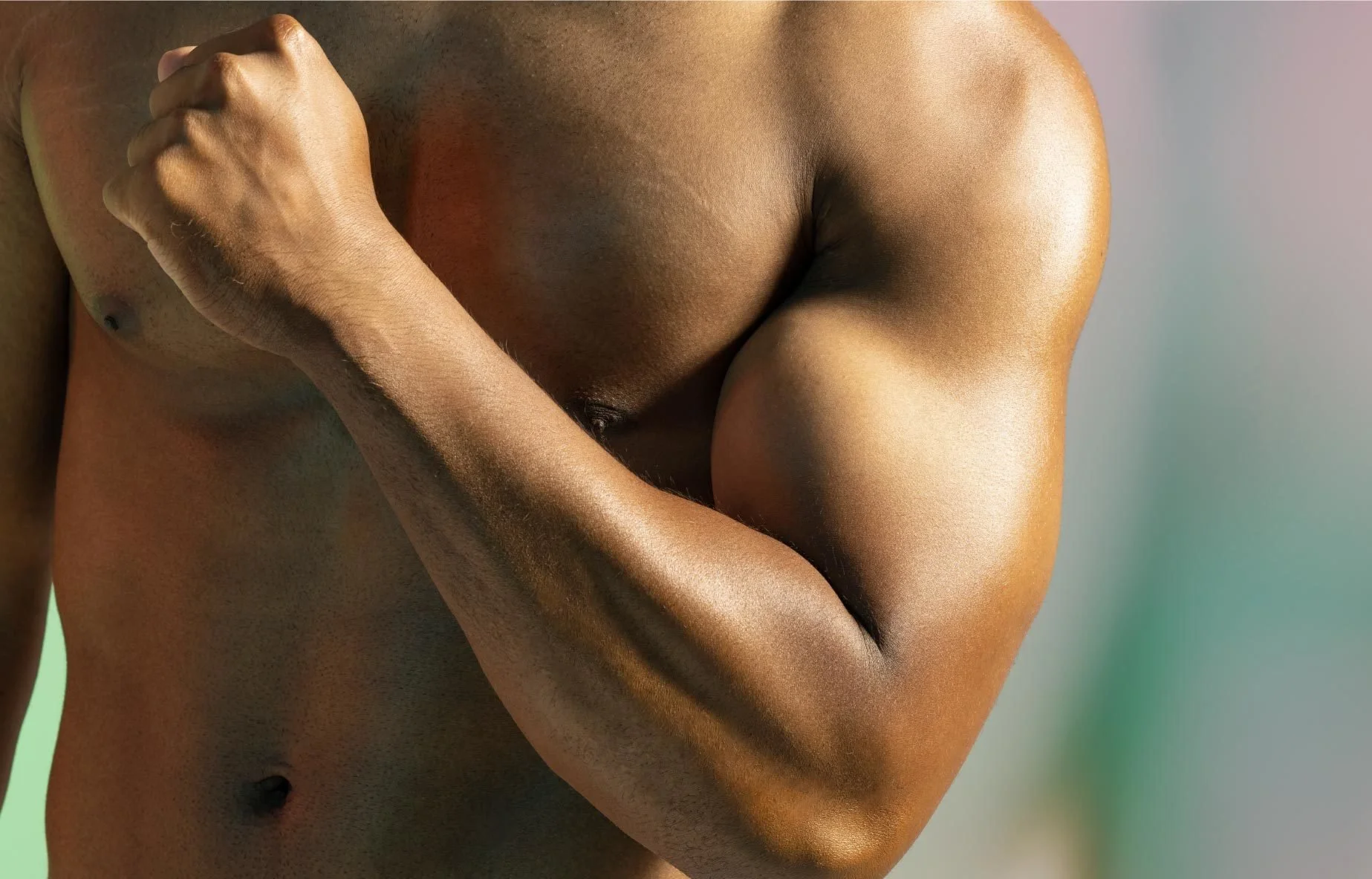 Close up of topless man's torso flexing his bicep in Nutiani shoot.