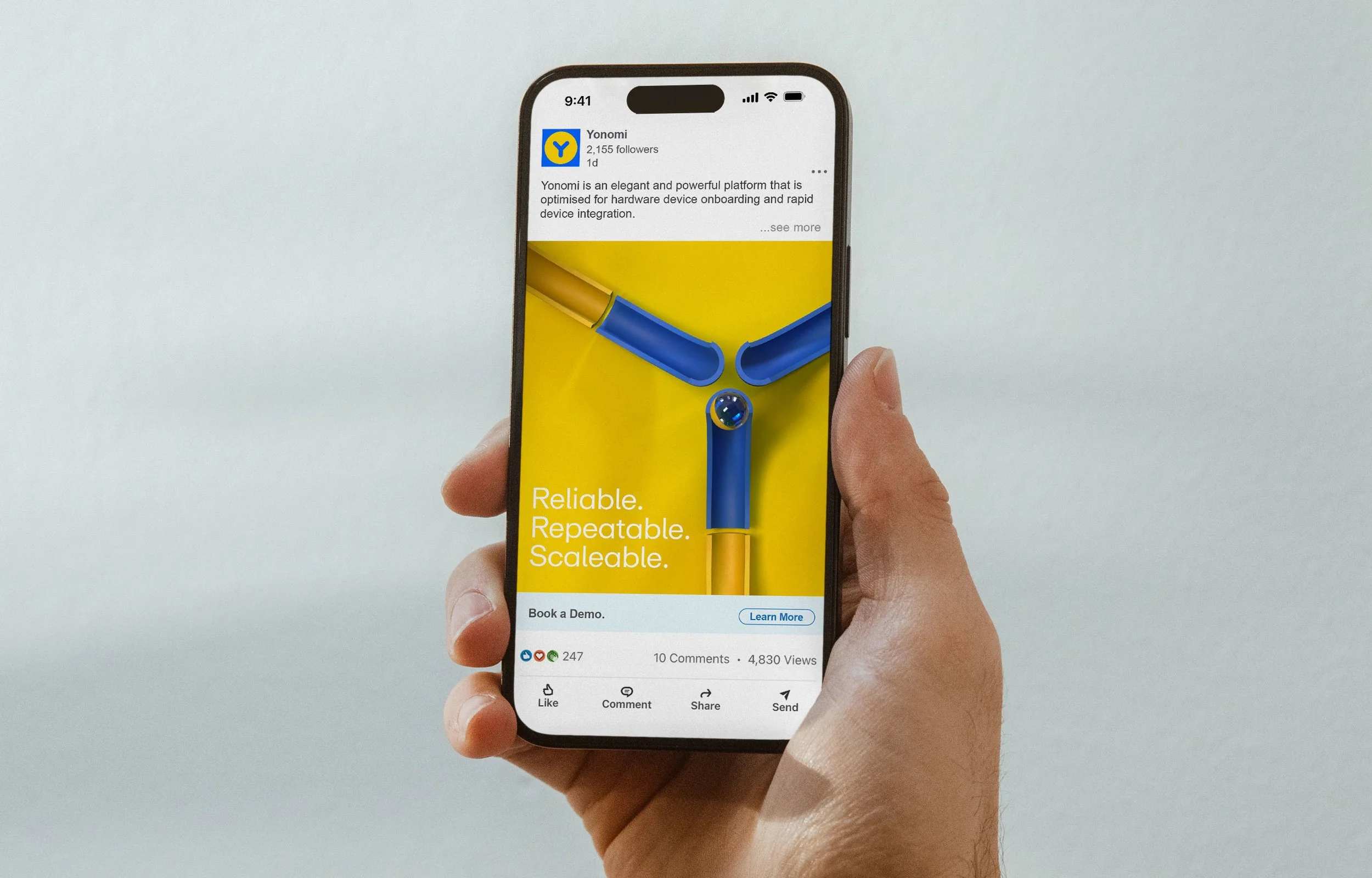 A hand holding a smartphone displaying a social media post about Yonomi, with a yellow background and a technical illustration of a device connected by blue and yellow tubes, accompanied by the text 'Reliable. Repeatable. Scaleable.'
