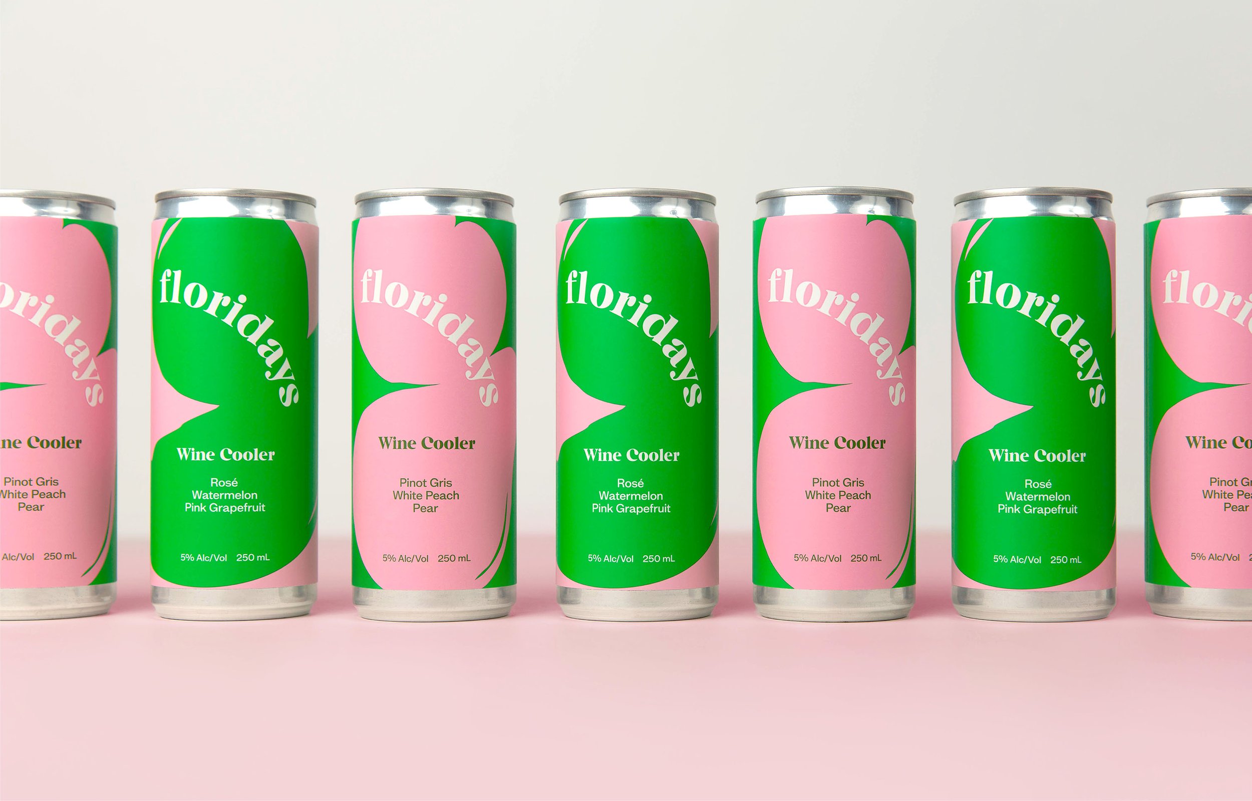 Seven cans of wine cooler arranged in a row on pink background, alternating pink and green labels with the word 'floridays' and flavors listed.