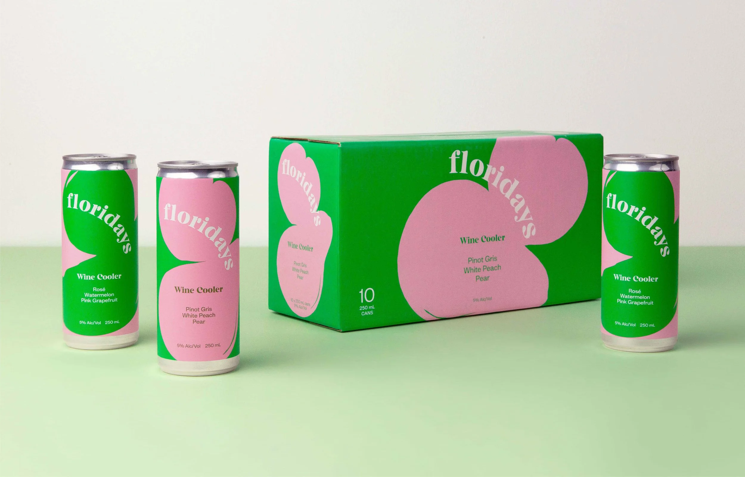 A box of Florida's Wine Coolers with 10 cans inside, along with three individual cans outside the box. The cans and box are decorated with pink and green labels featuring a large pink peach shape and the brand name 'floridays'. The cans list flavors such as rosé, watermelon, pink grapefruit, white peach, and pear. The cans and box indicate 5% alcohol by volume and 250 ml each.