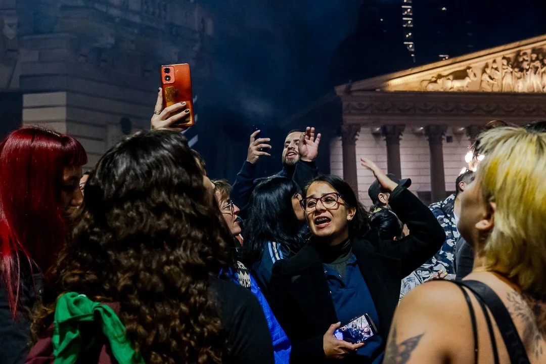 Grupo de personas sonriendo en la calle, algunas con cabello de colores y expresiones de felicidad.