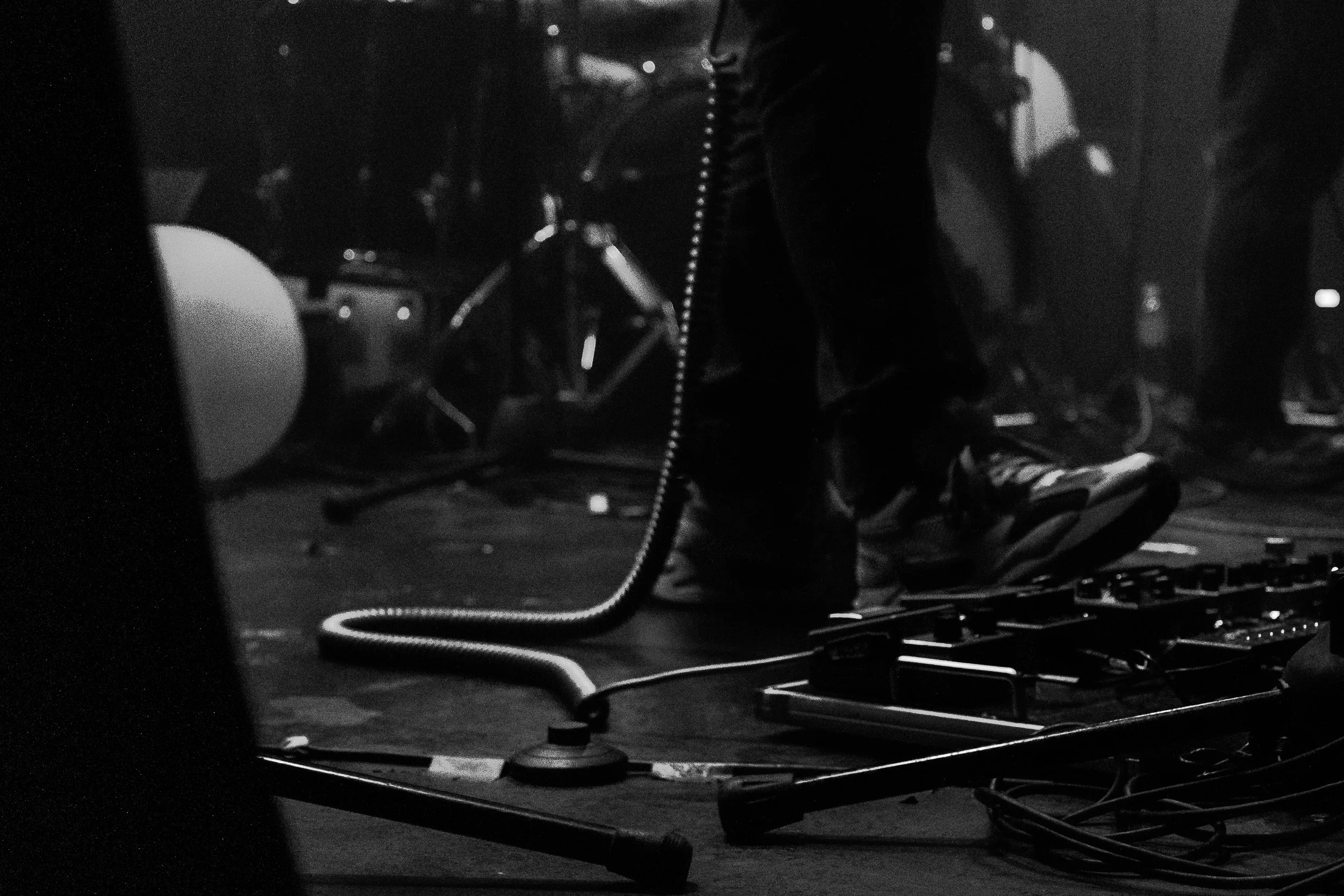 Persona en un escenario con equipo musical, el suelo y cables visibles