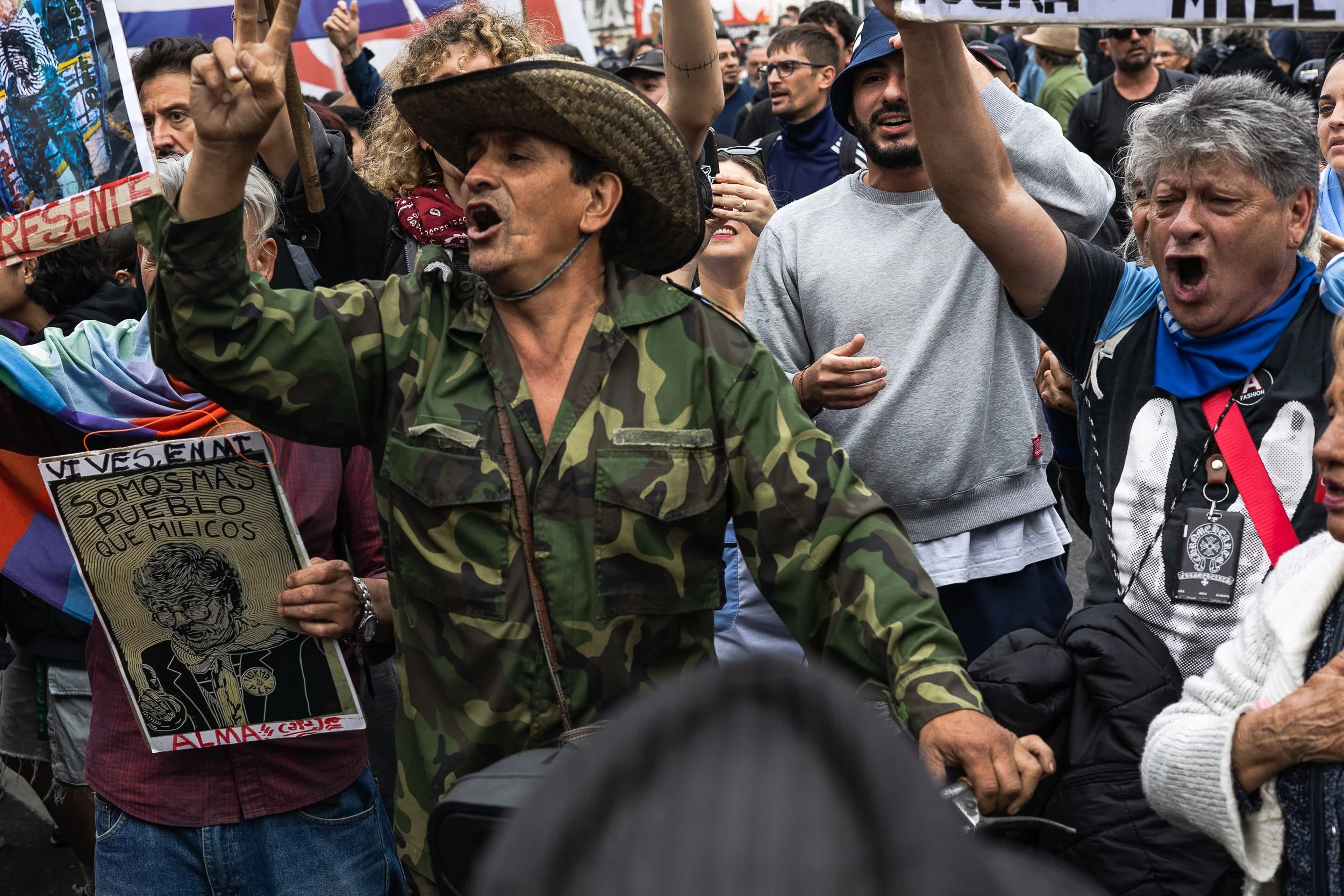 Grupo de personas participando en una manifestación, algunas con carteles y expresando emociones fuertes.