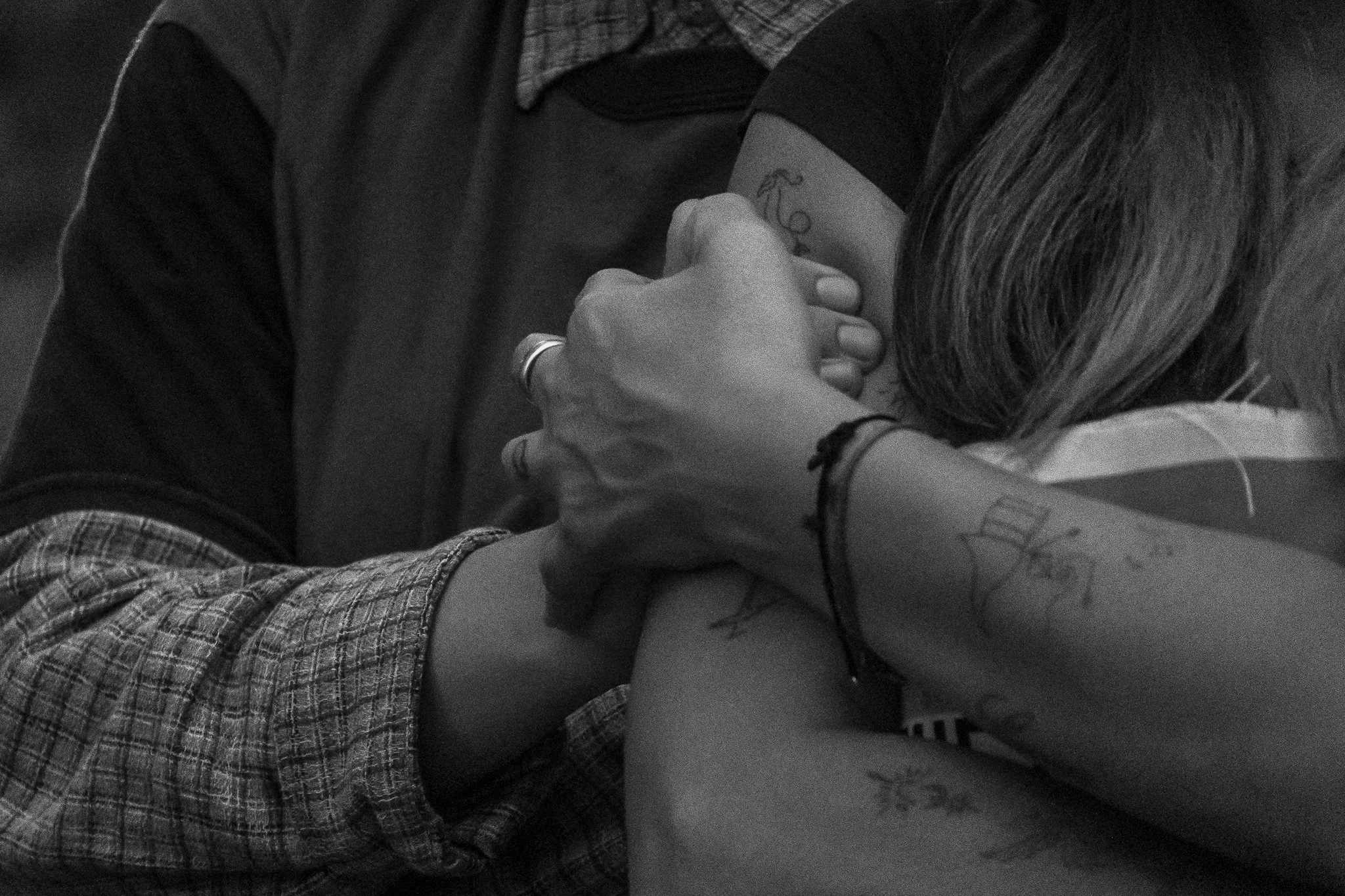 Primer plano de una mano de una persona tocando la mano de otra persona. La imagen es en blanco y negro, y ambas personas parecen estar en un contacto cercano.