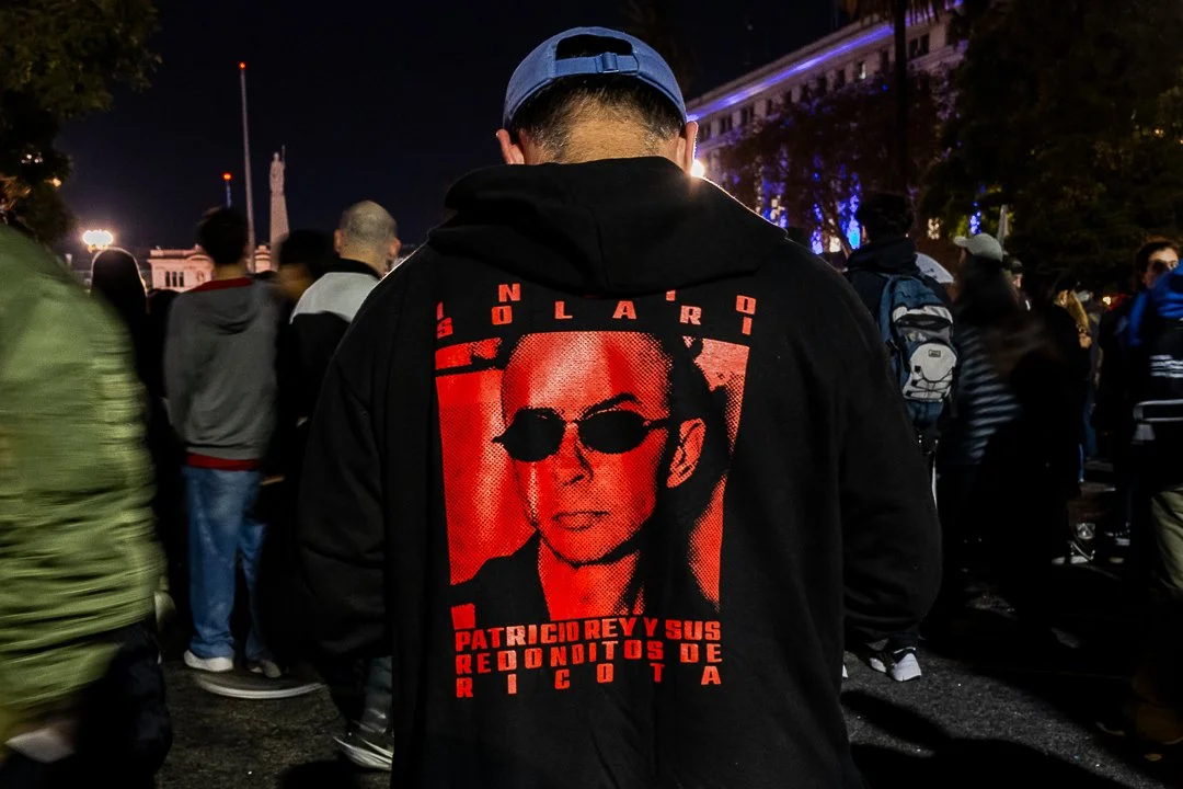 Persona con una remera negra que tiene una imagen del Indio Solari: un hombre con gafas oscuras y un texto en rojo que dice "Patricio Rey y sus Redonditos de Ricota".