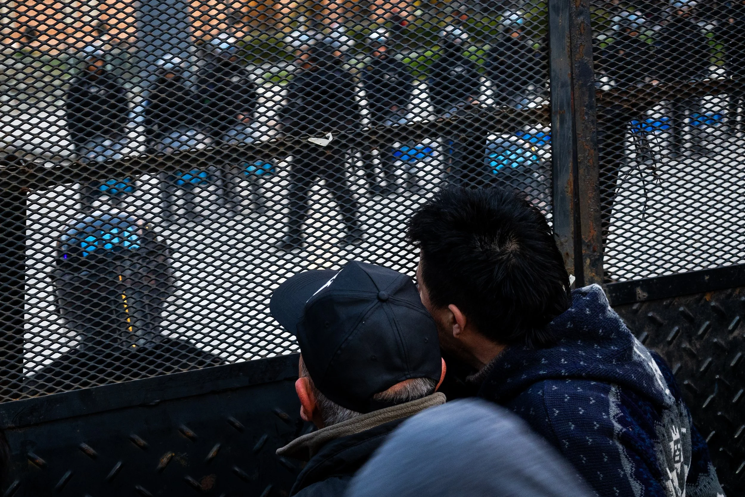 Personas observando a policías a través de una reja en una protesta o manifestación.