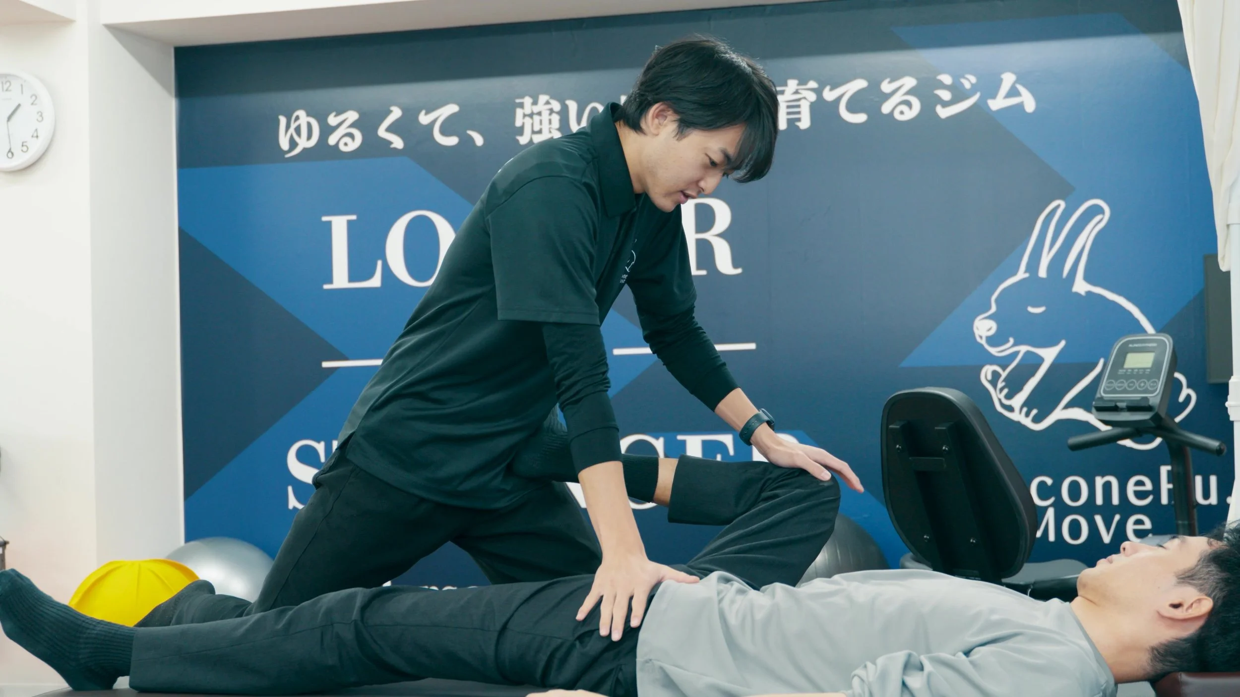 トレーナーが横になっている人の腰を手で押しているダイエットのシーン