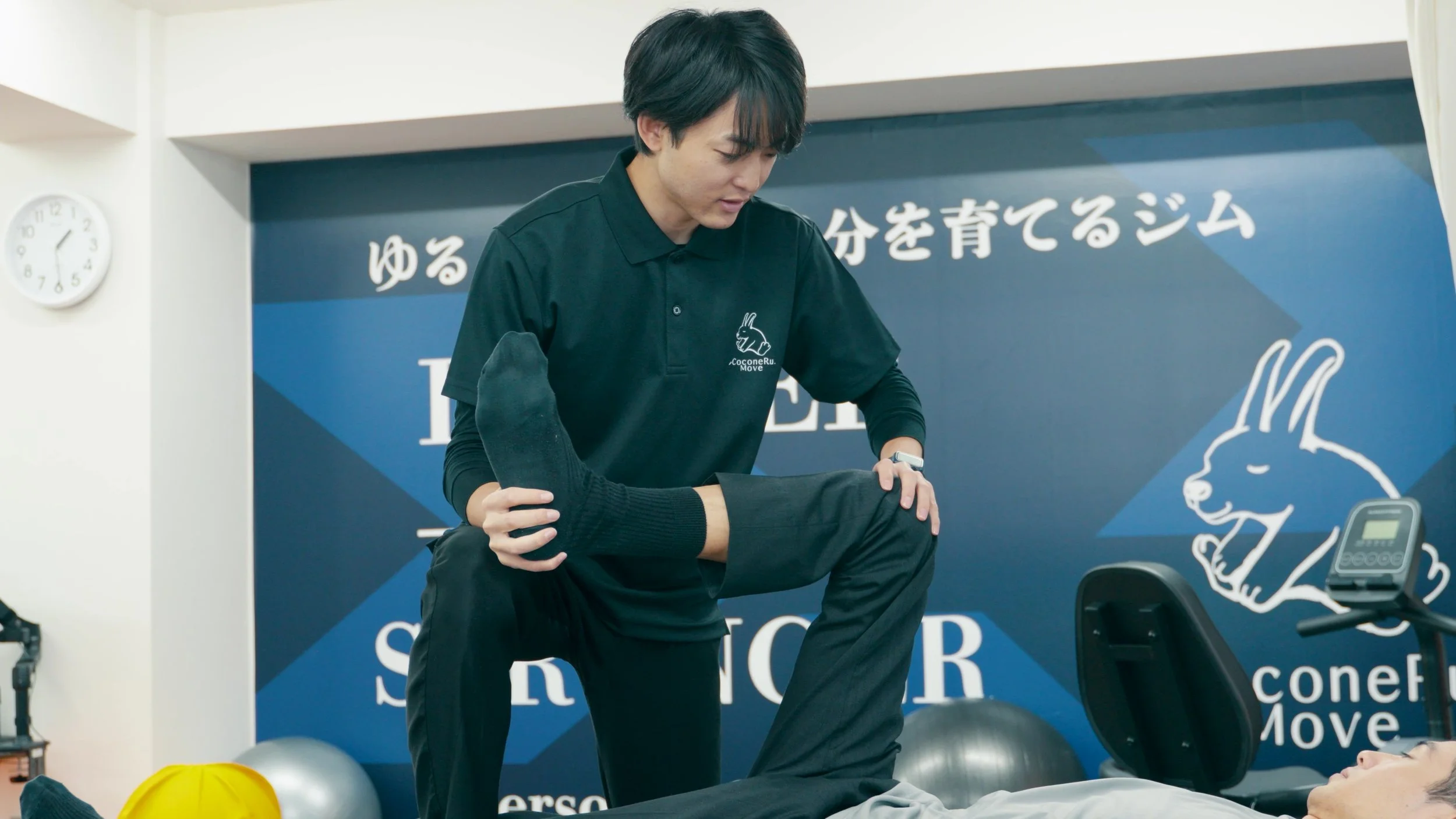 柔道整復師が患者の脚を持ちながらストレッチをしている場面