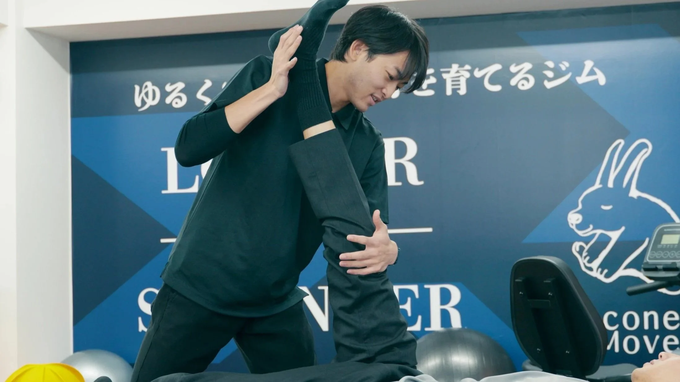 柔道整復師が患者の膝をサポートしながら運動療法を行う様子