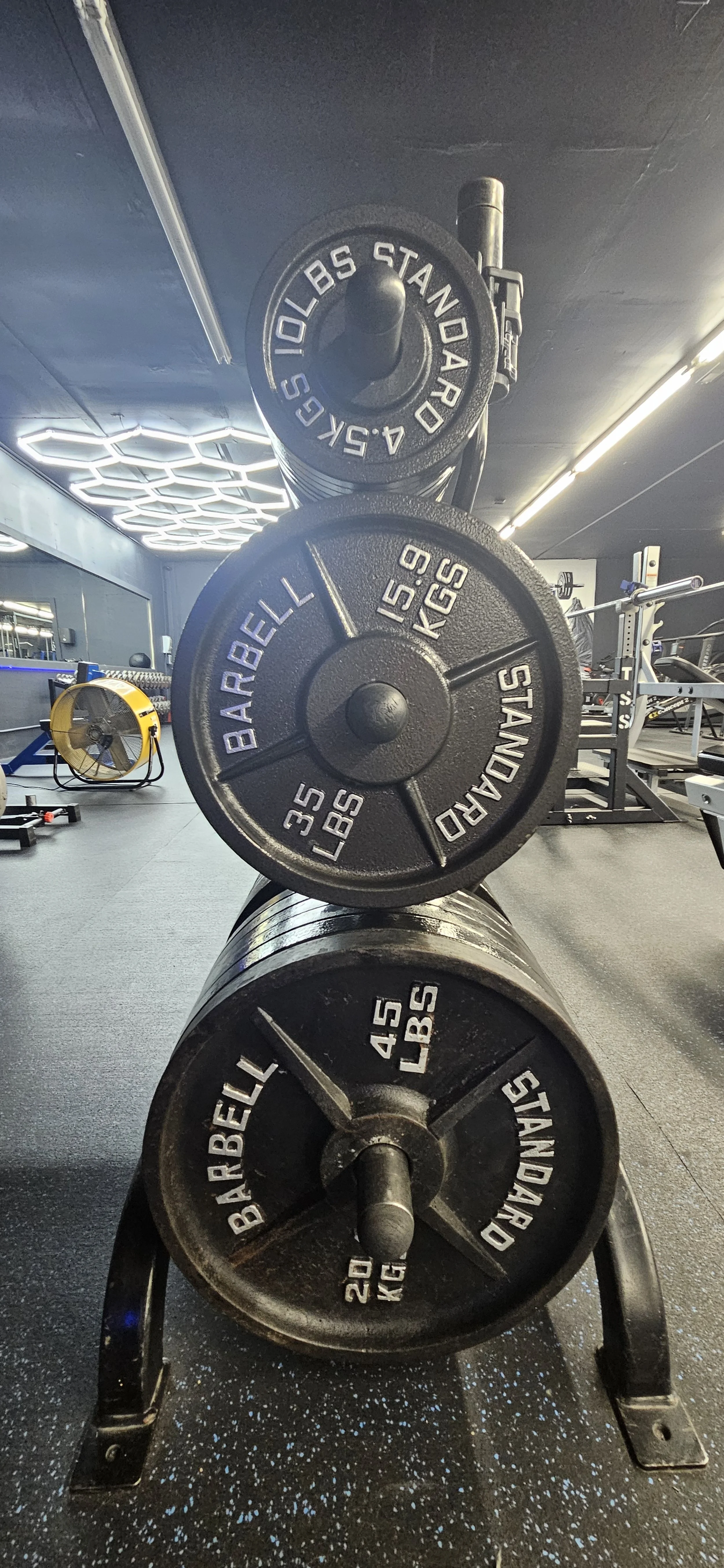 Stacked weight plates at a gym, including 10-pound, 35-pound, and 45-pound plates.