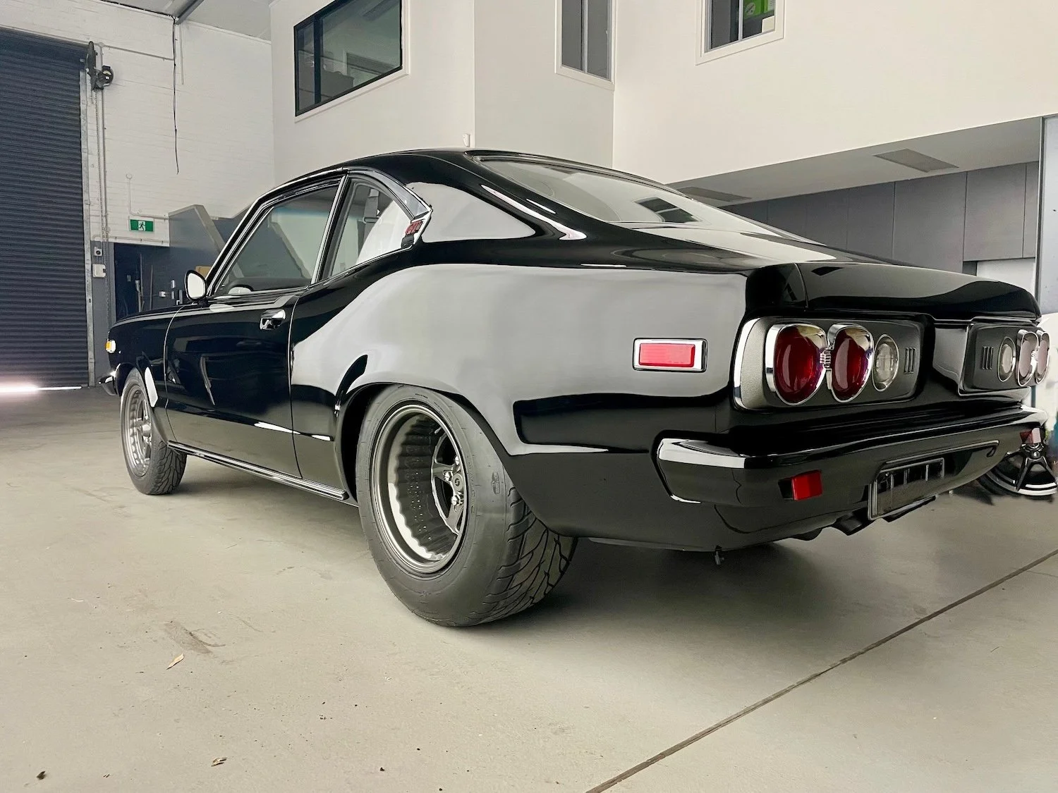 Autoprep Sydney Car Detailing - A black and white classic car parked indoors with a modern building in the background.
