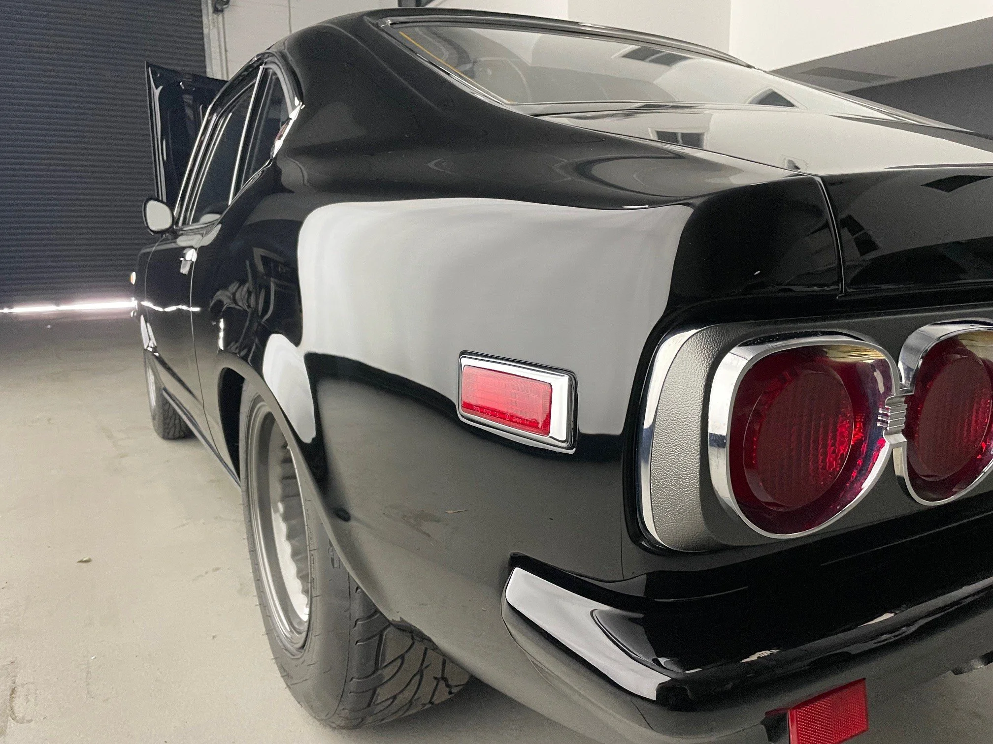 Autoprep Sydney Car Detailing - Black classic car with dual round tail lights and chrome accents, parked indoors.