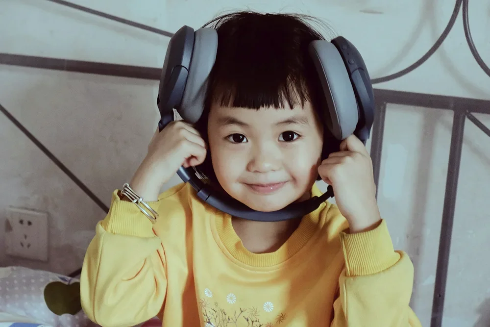 A young child smiling and wearing large over-ear headphones.