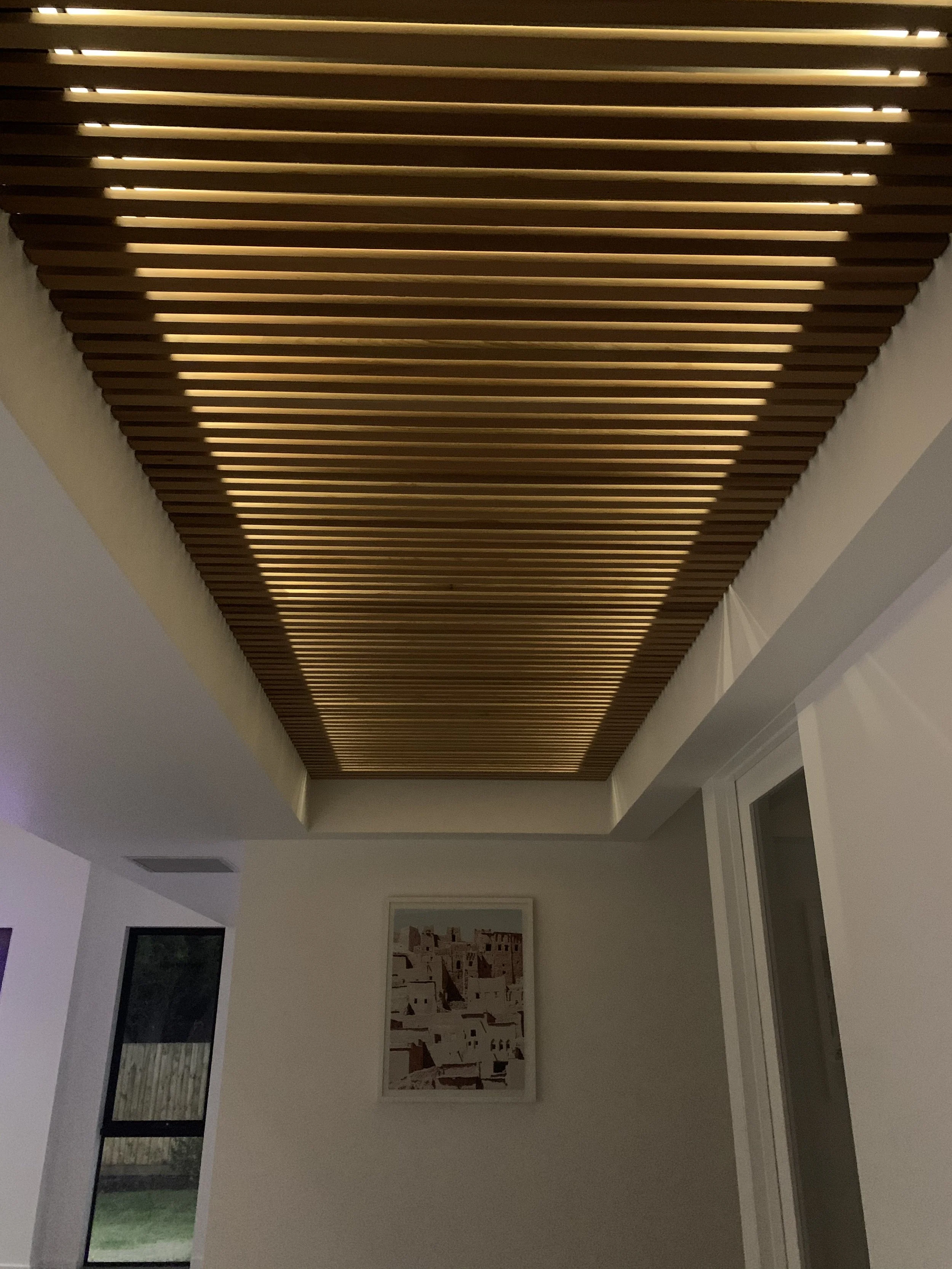 Interior ceiling with wooden slats and hidden lighting, part of a modern home interior.