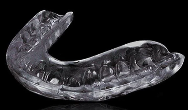 Close-up of a clear, curved dental mouthguard against a black background.