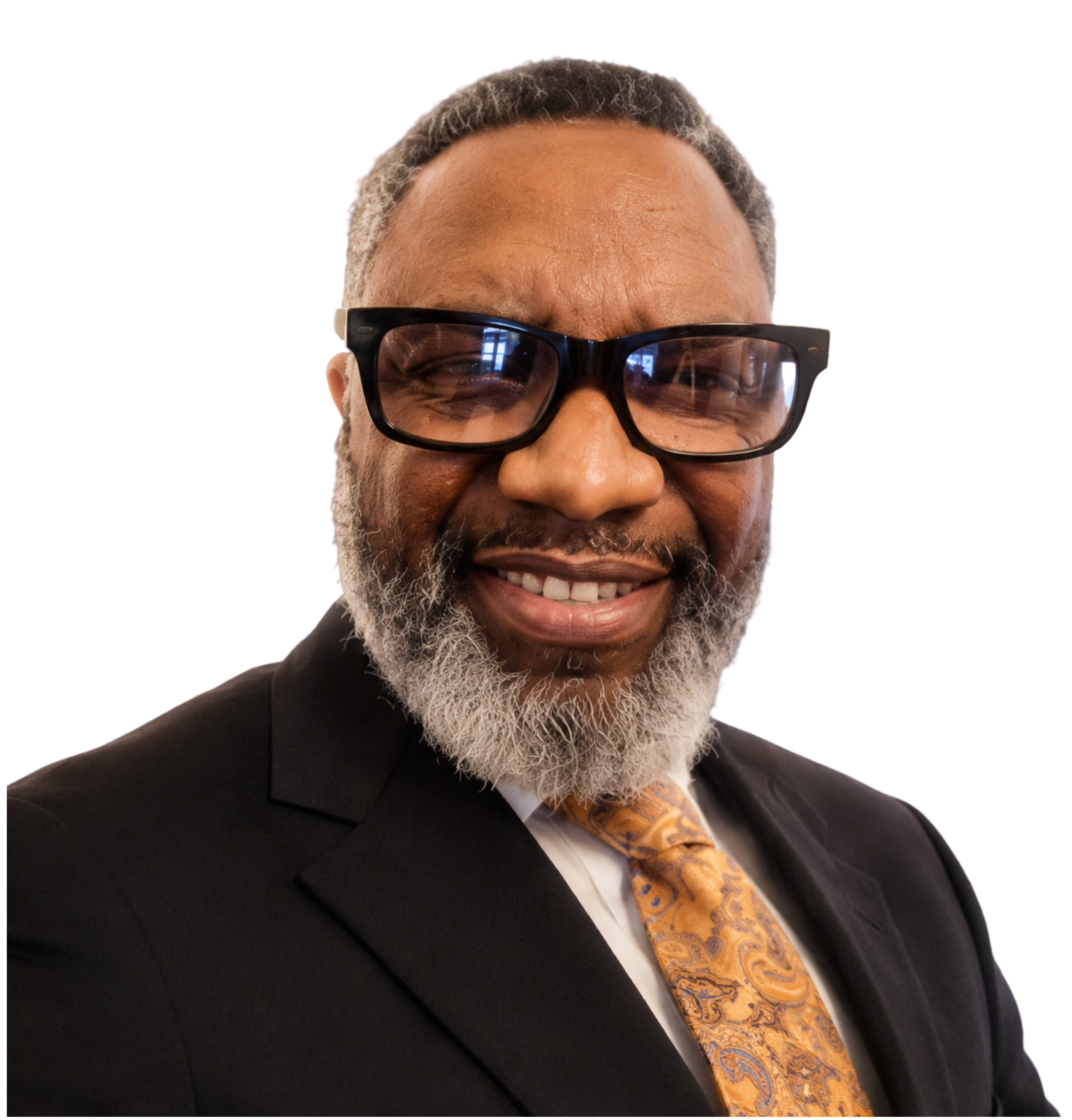 Close-up of a smiling man with gray hair, beard, wearing glasses, a tuxedo, and a yellow patterned tie.