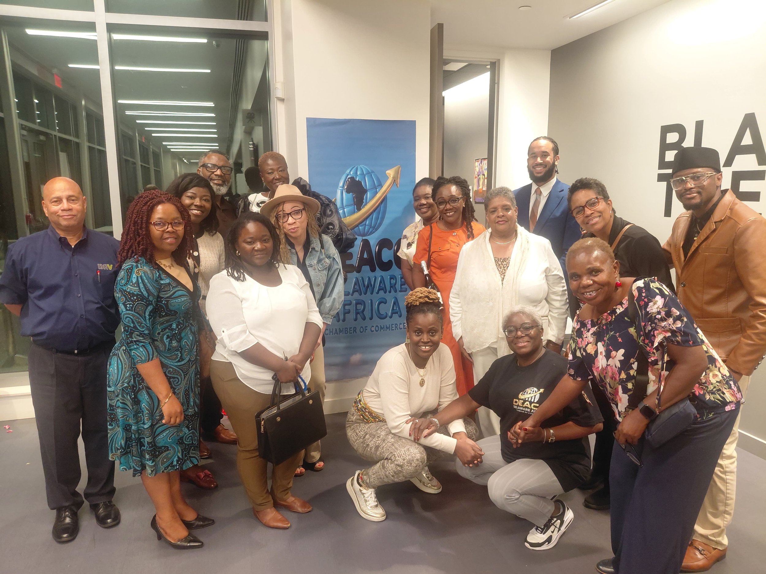 A diverse group of men and women smiling and posing together at an indoor event, standing in front of a blue and white banner that reads 'PEACE AWARD AFRICA' with a logo of a globe and a gold arrow.
