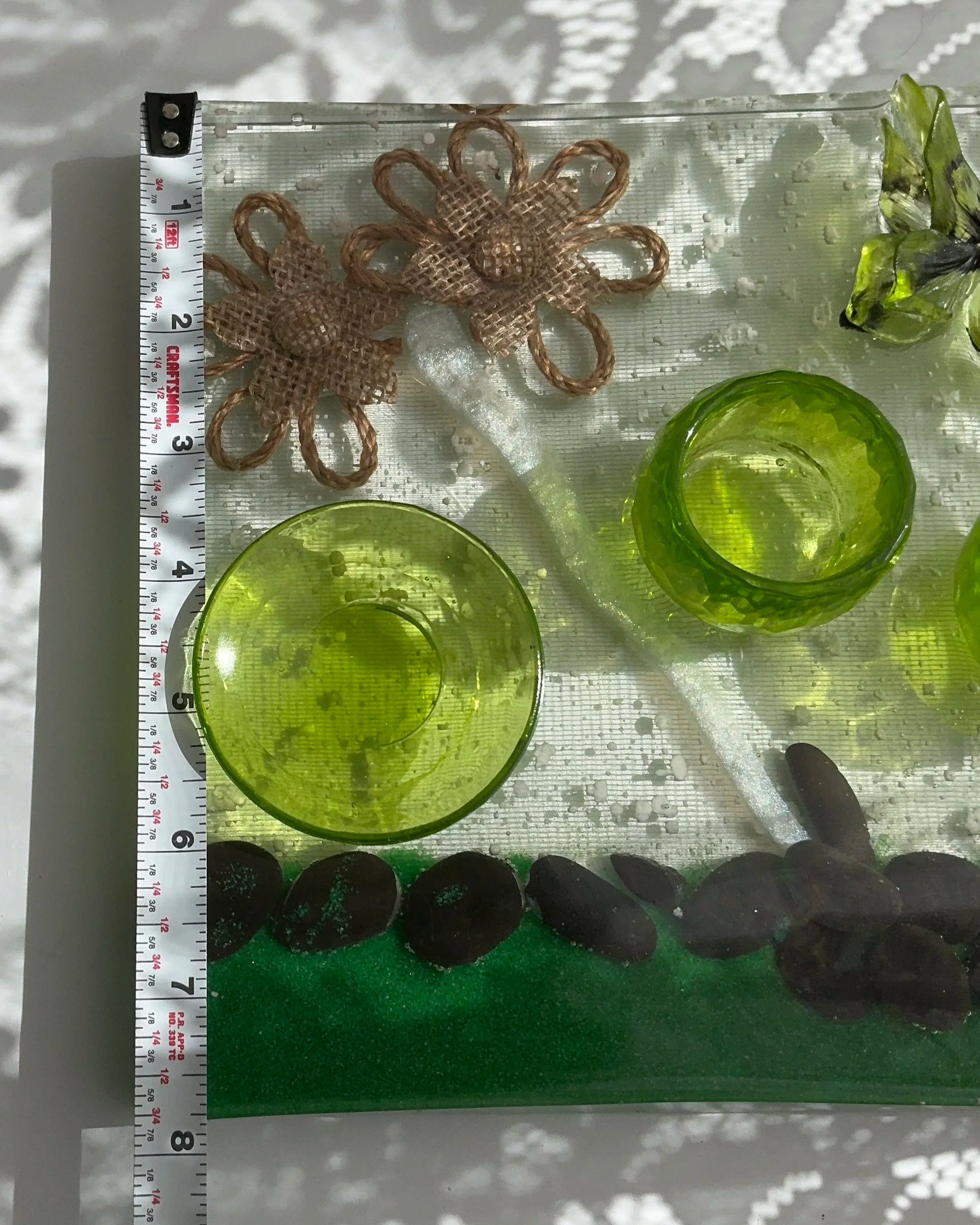 A measuring tape beside the handcrafted resin propagation station shows its approximately 8-inch length, providing scale for the green plant holders, embedded flowers, black stones and clear resin bas