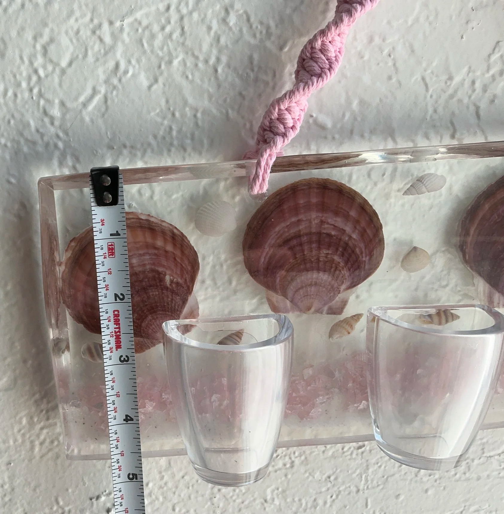 Close view of the clear resin panel beside a vertical measuring tape showing the approximate height of the rectangular shell-filled base.