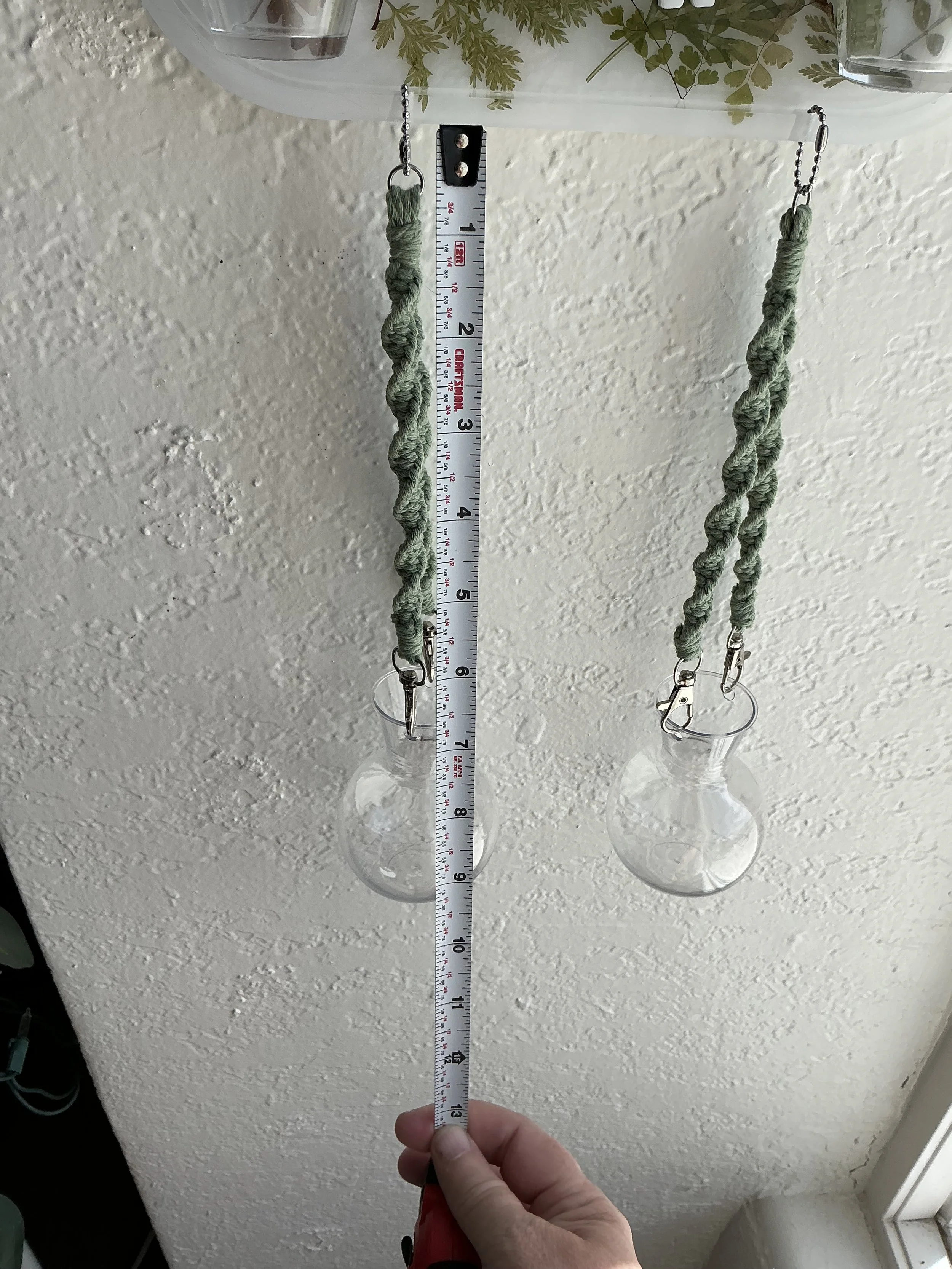 Close measurement view of the detachable lower section, showing each macramé hanger and round propagation vase extending approximately ten inches below the resin panel.