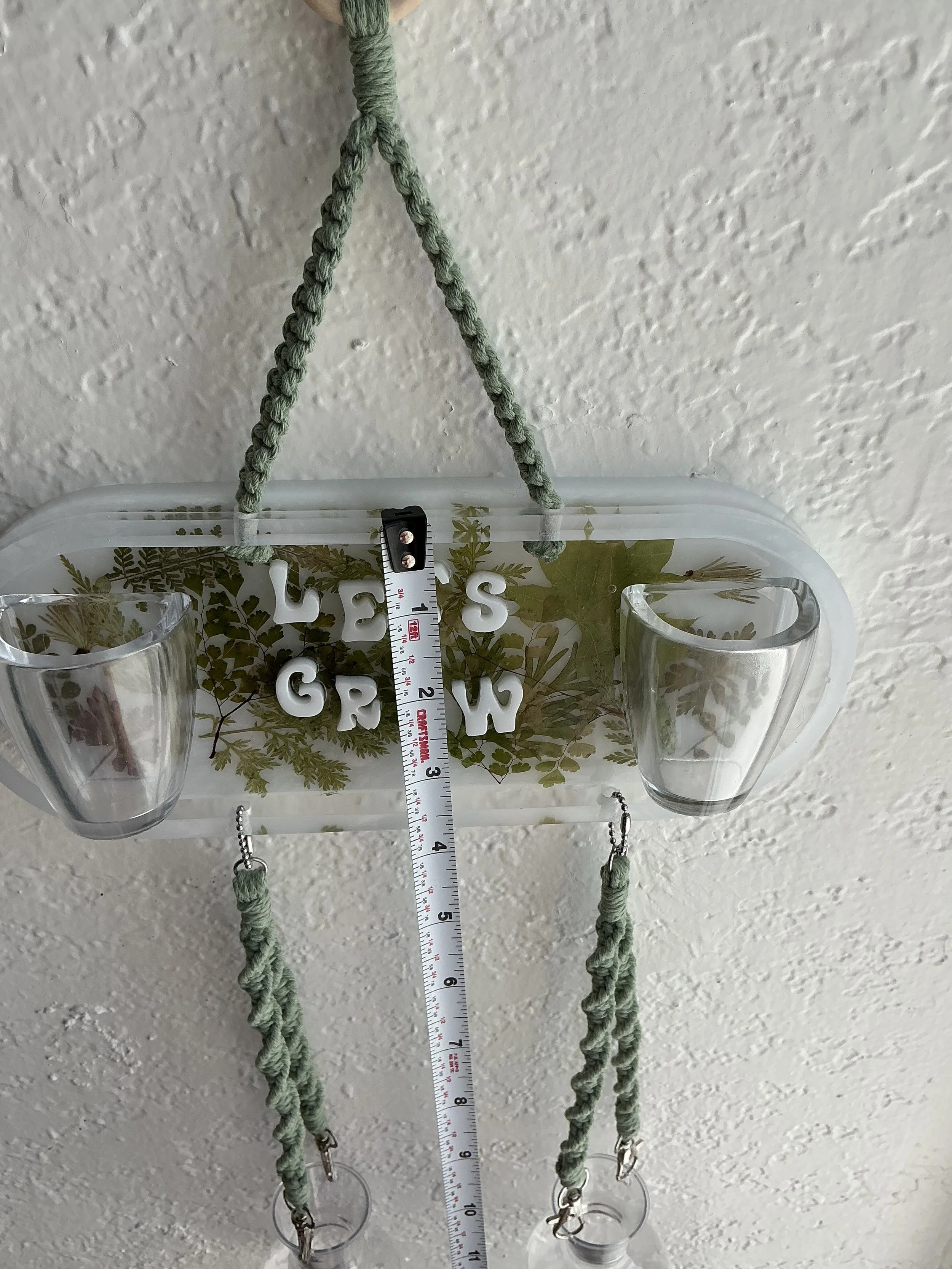Front measurement view of the botanical resin panel and hanging vessels, showing the panel at approximately four inches tall and the lower section extending beneath it.