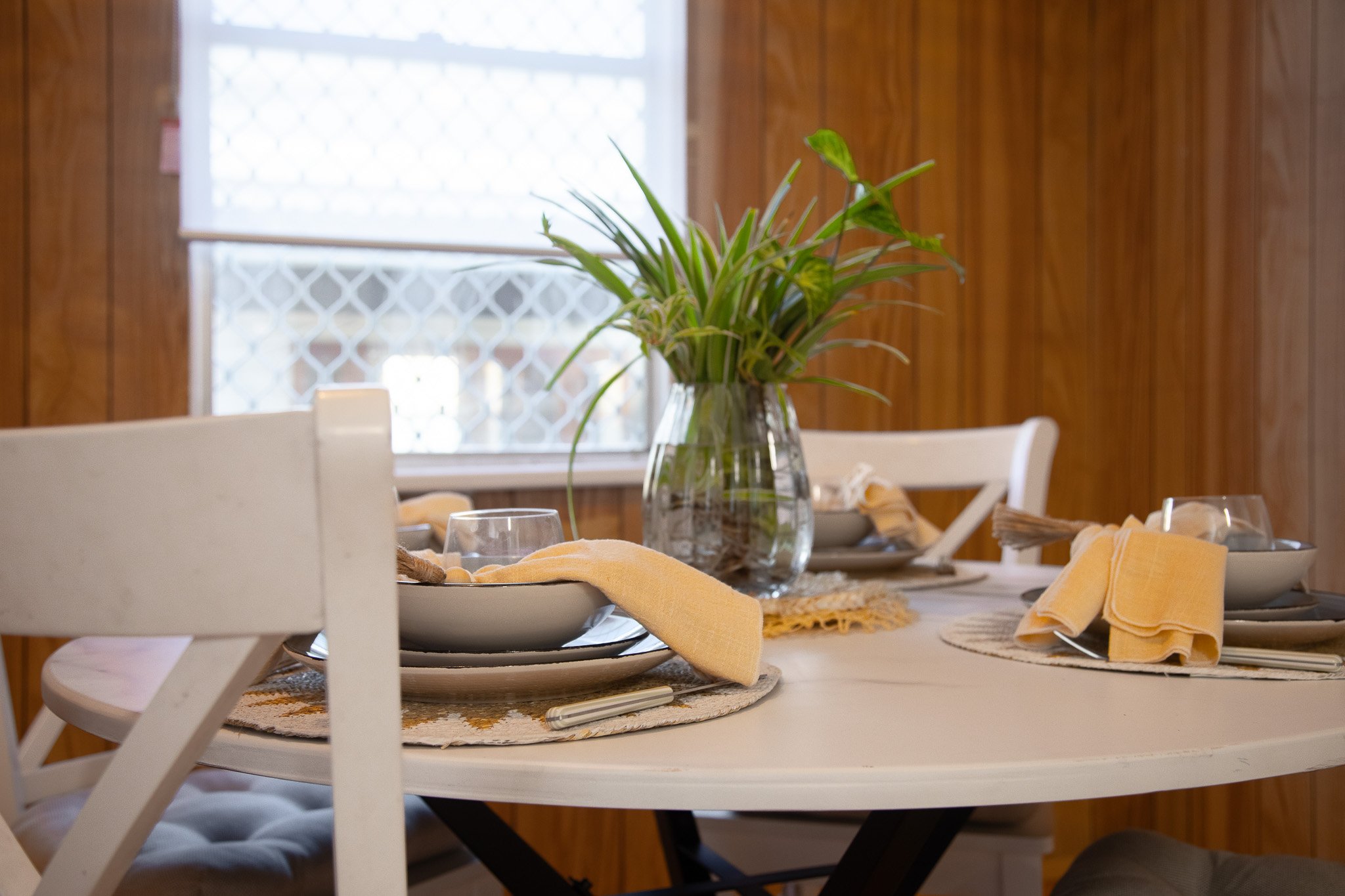 A modern bathroom with a glass shower, a white vanity with a round mirror, and a toilet next to a frosted window.