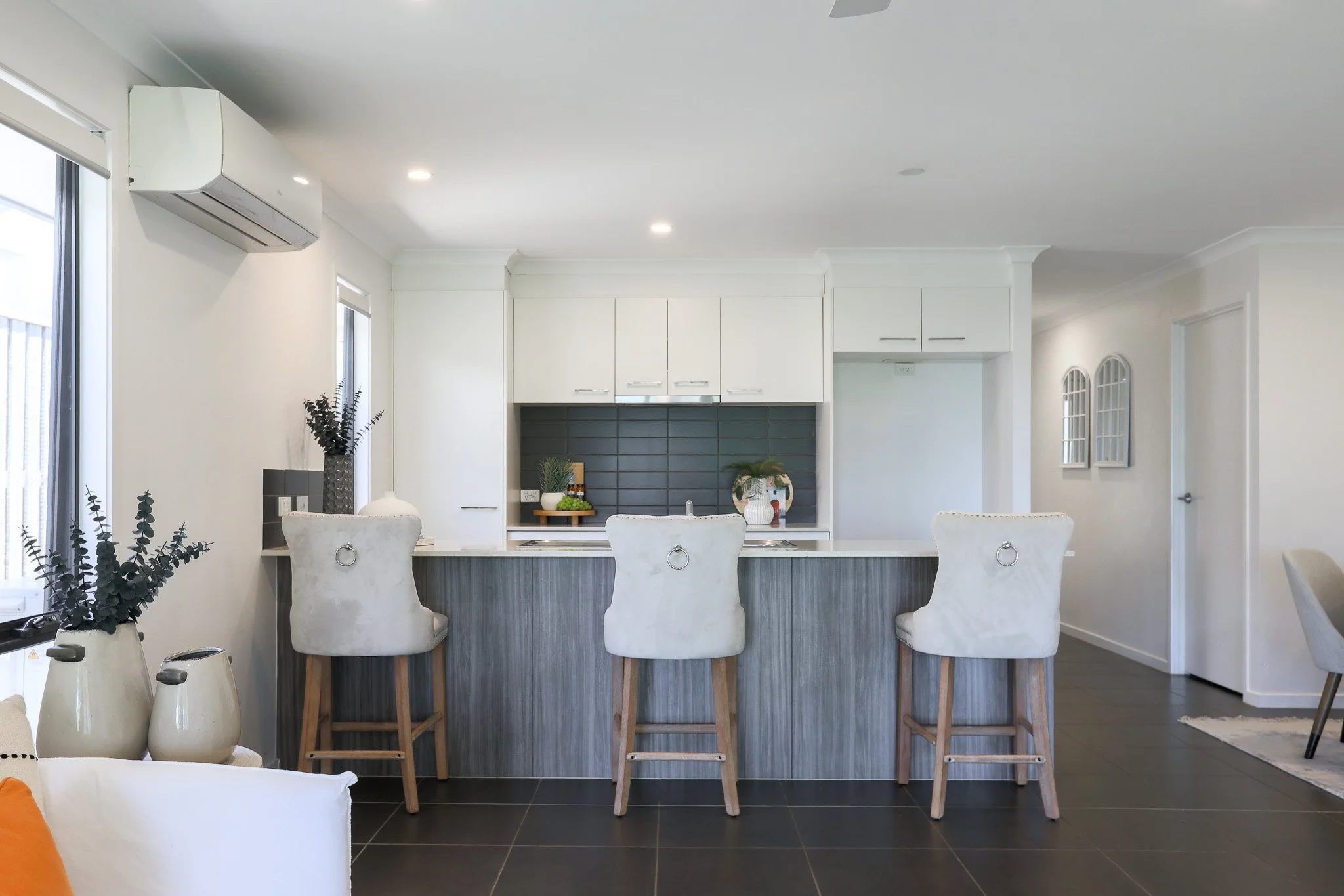 Empty room with white walls, gray carpet, sliding glass door with security screen, ceiling fan with light, and small adjoining laundry room.