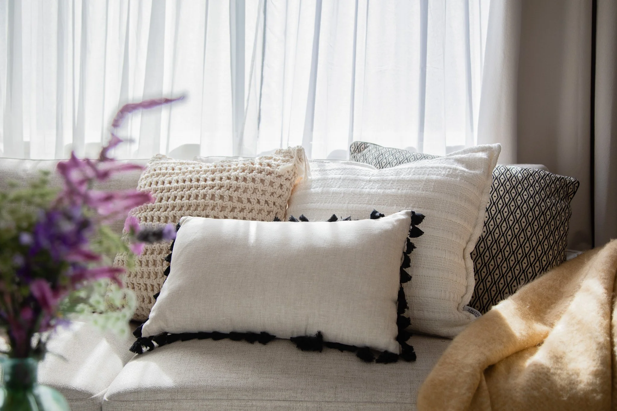 Empty living room with white walls, light wood flooring, ceiling fan, large window with security screen, sliding glass door leading to backyard, and an air conditioning unit.